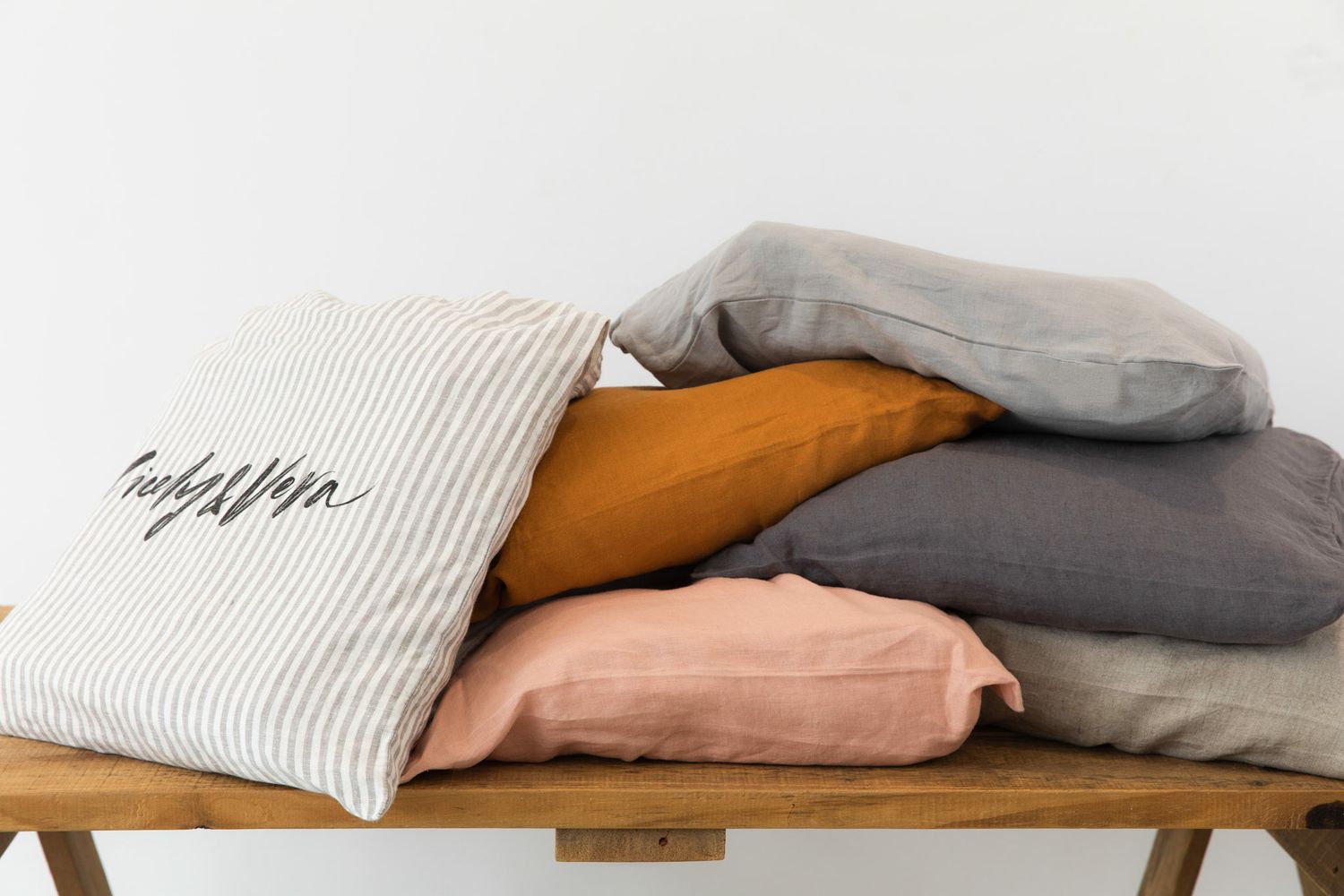 Neatly folded and stacked cozy textiles in neutral colors displayed on wooden surface.