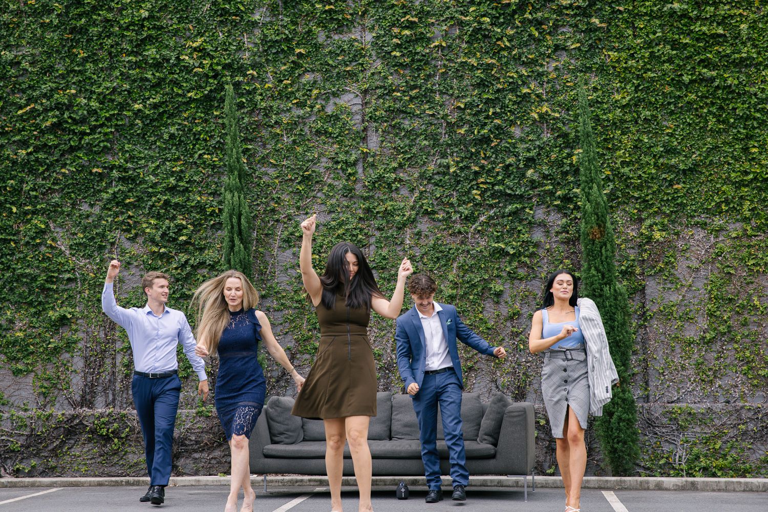 Engaged couple walks and poses playfully together in a series of romantic photos against an ivy-covered wall.