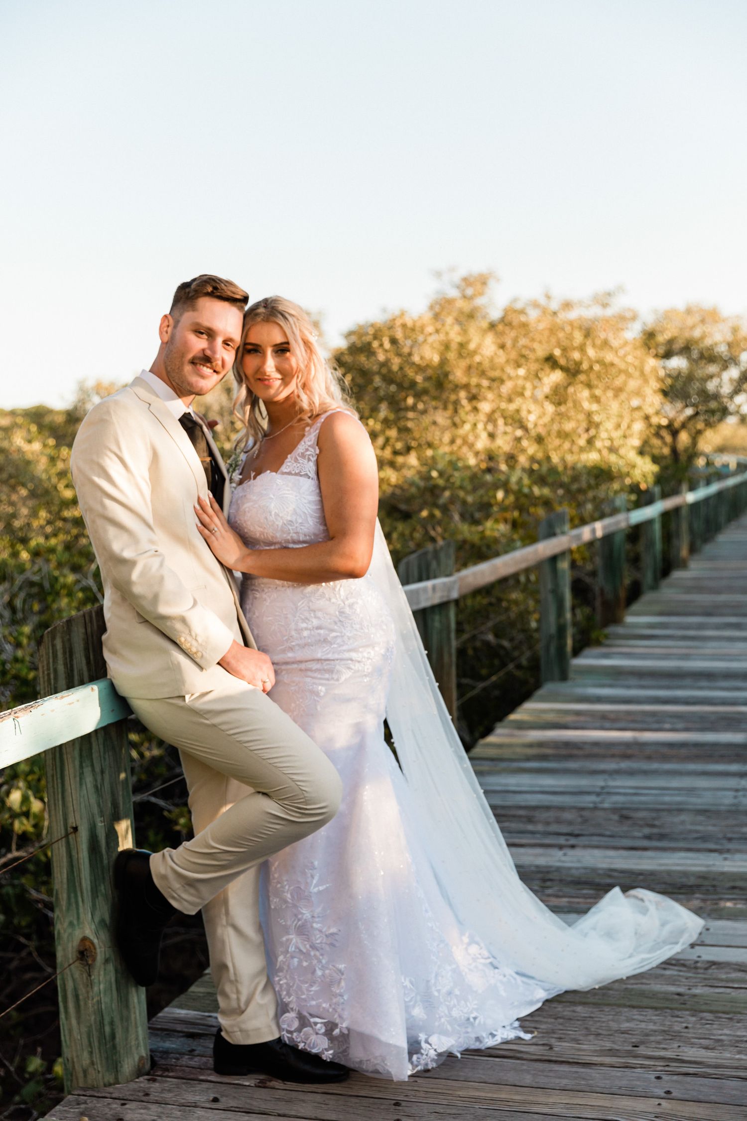 Romantic couple photos on wooden boardwalk during sunset.