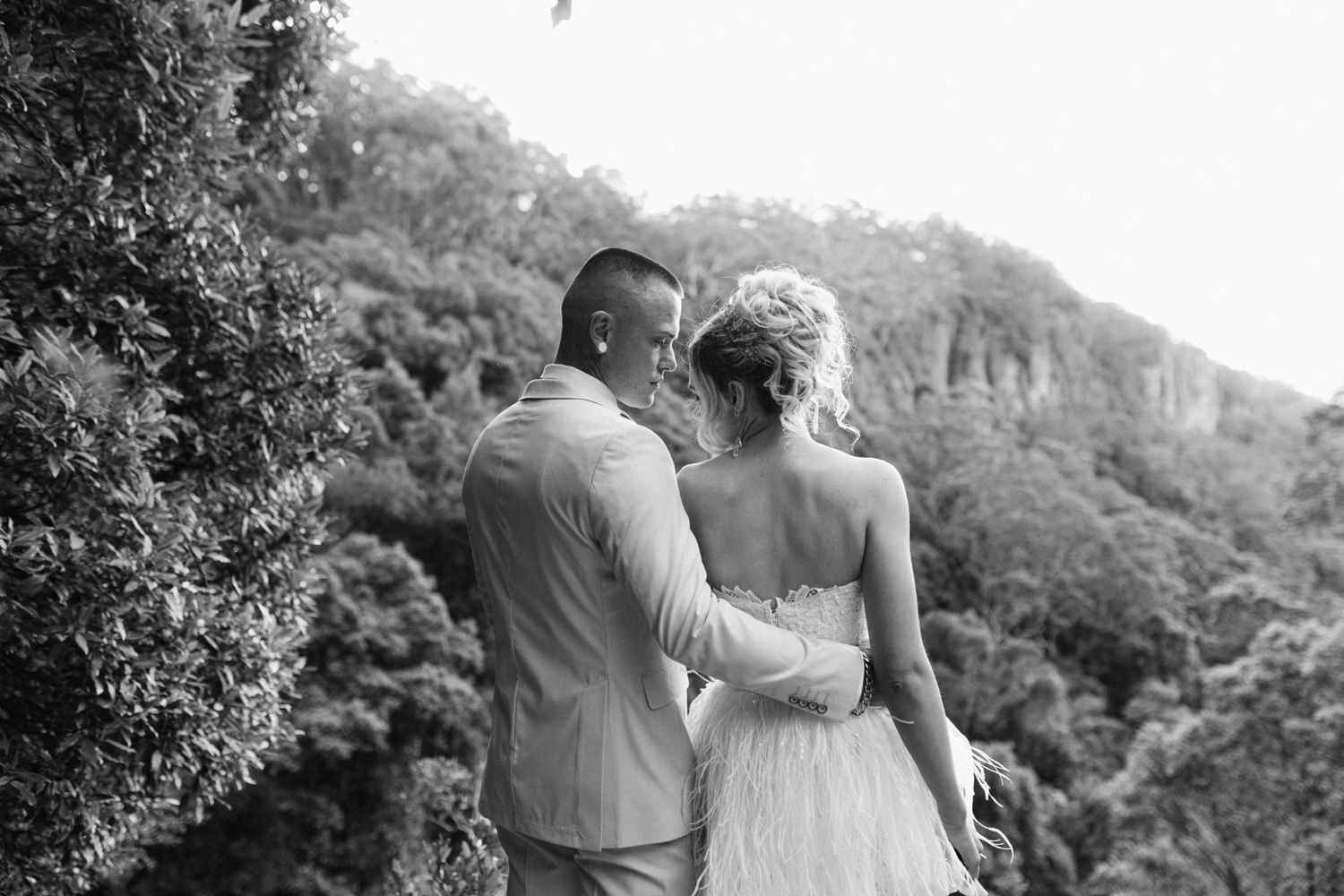 A romantic black and white photo series of a couple embracing and kissing in a garden setting.