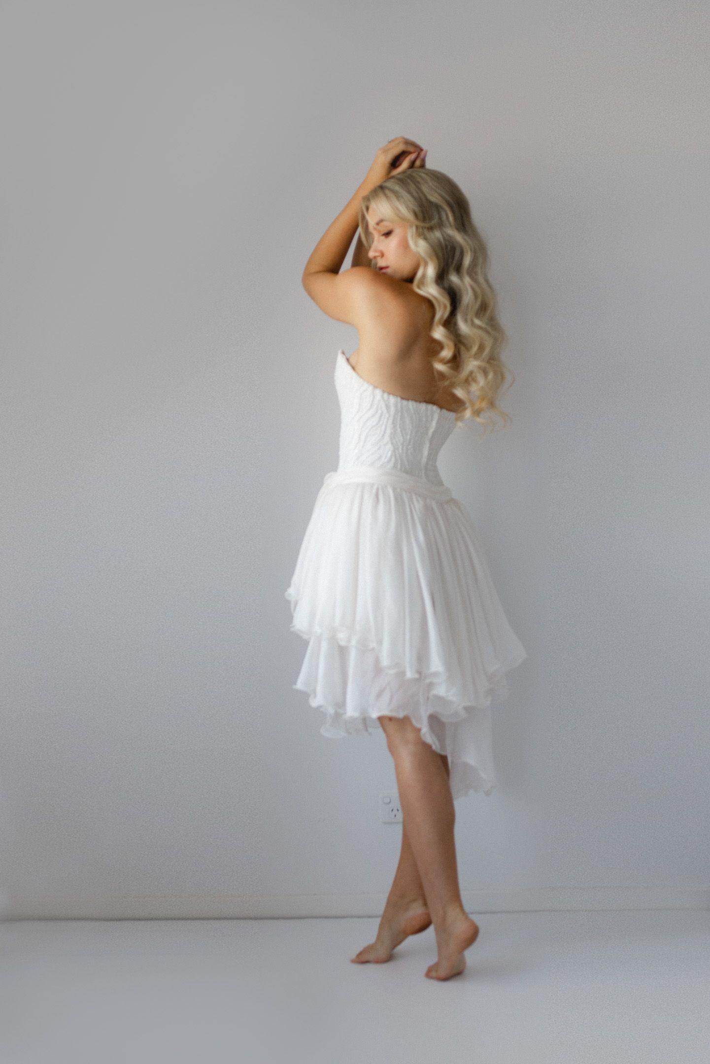 A figure in a flowing white dress dances gracefully against a gray backdrop in a series of artistic movement shots.