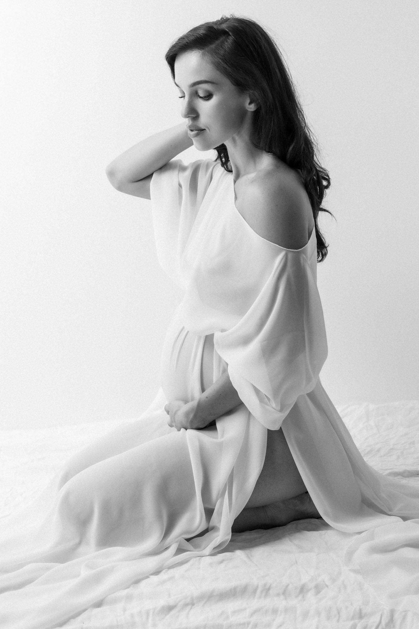 Artistic black and white boudoir photo series showing feminine silhouette draped in flowing white fabric on bed.