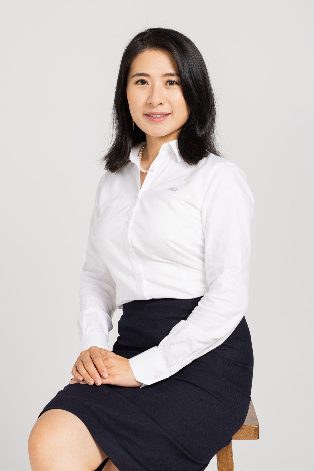 Professional portrait series of someone wearing a crisp white button-down shirt and navy skirt in studio lighting.