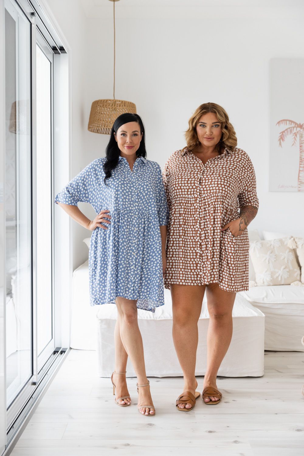 Two models wearing patterned mini dresses in blue and brown tones against white interior.