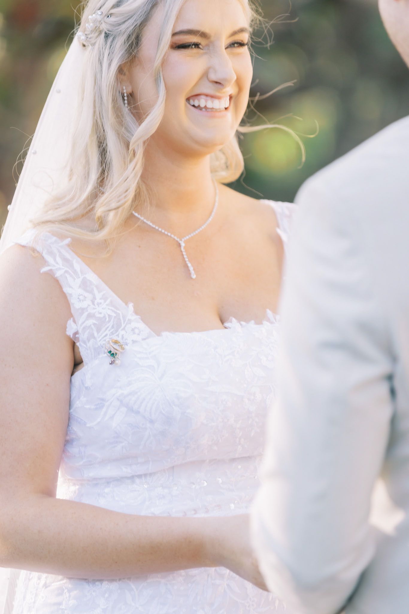 Close-up shots of bride in white lace dress during outdoor ceremony.