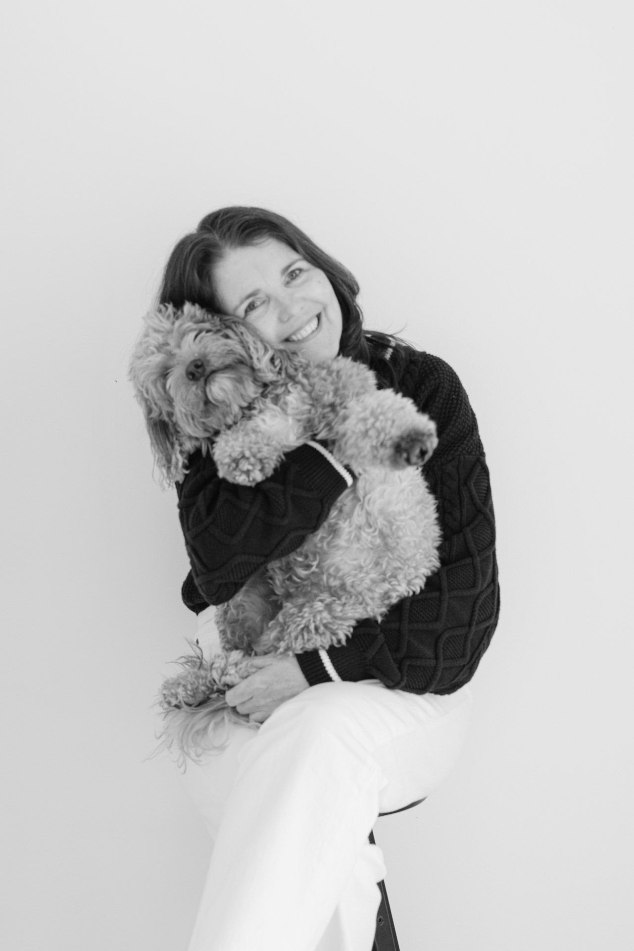 A series of black and white photos showing a person in dark clothing embracing a fluffy white dog.
