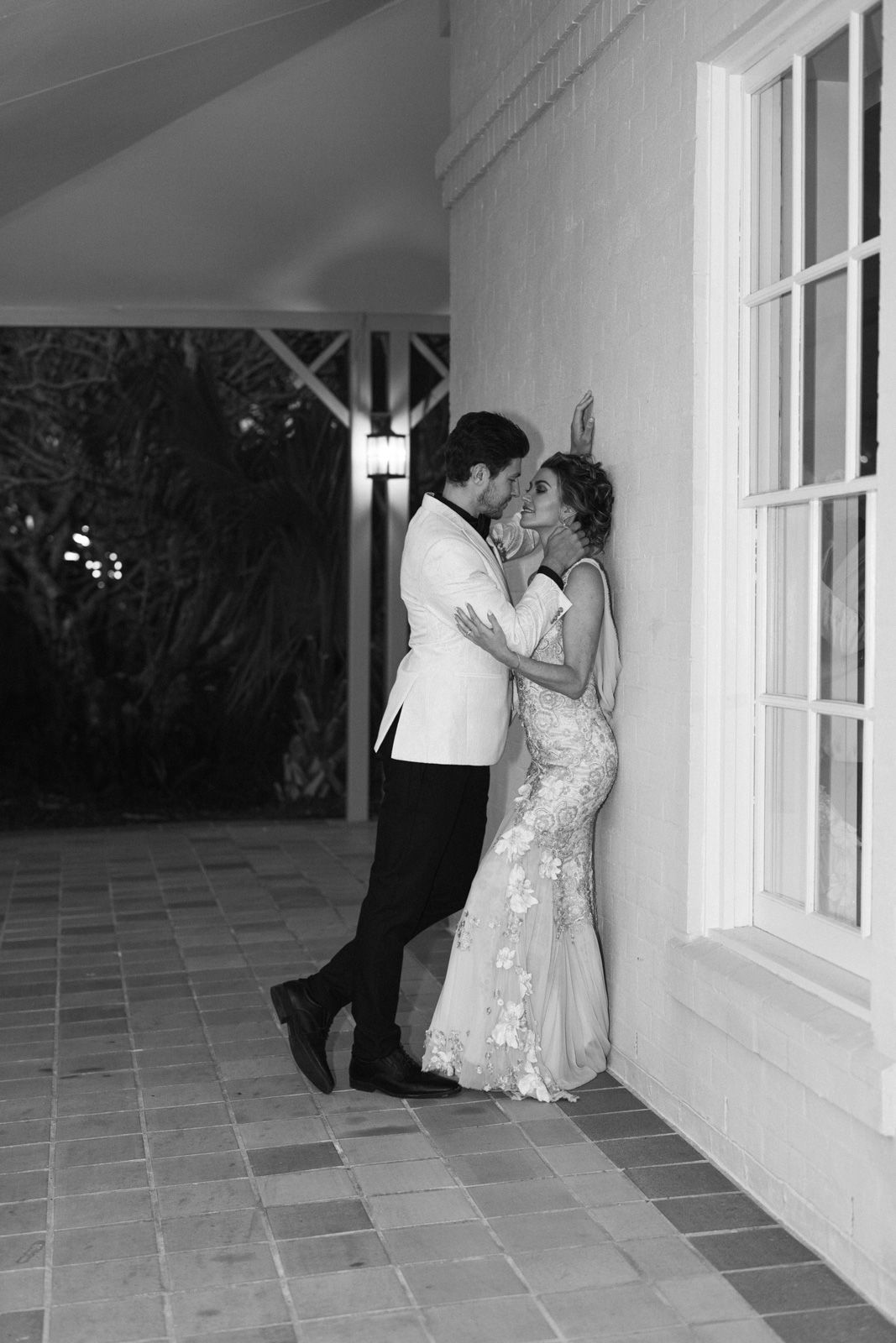 A romantic black and white photo sequence shows a couple in wedding attire sharing intimate moments along a covered walkway.