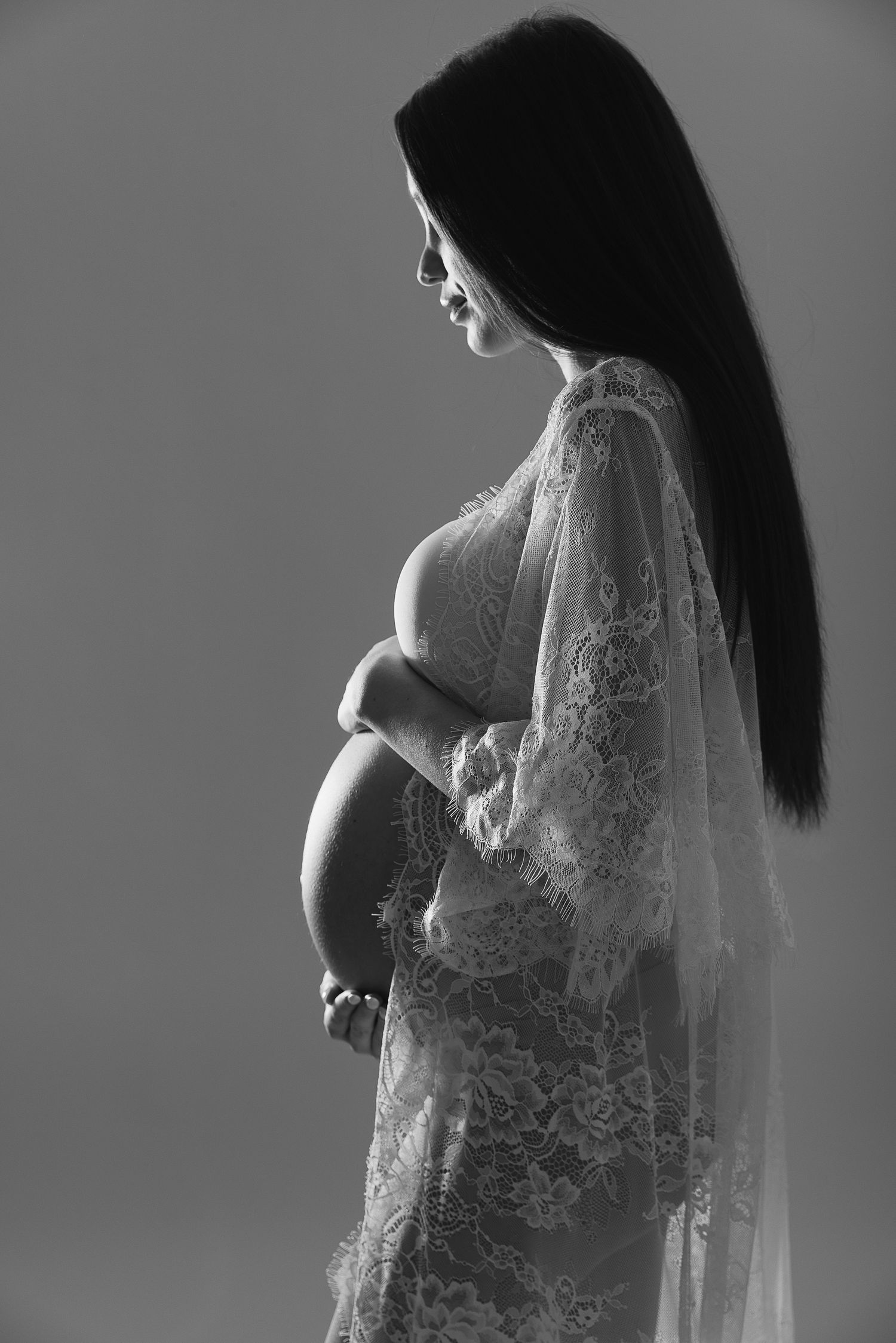 Black and white maternity silhouette wearing delicate lace gown.
