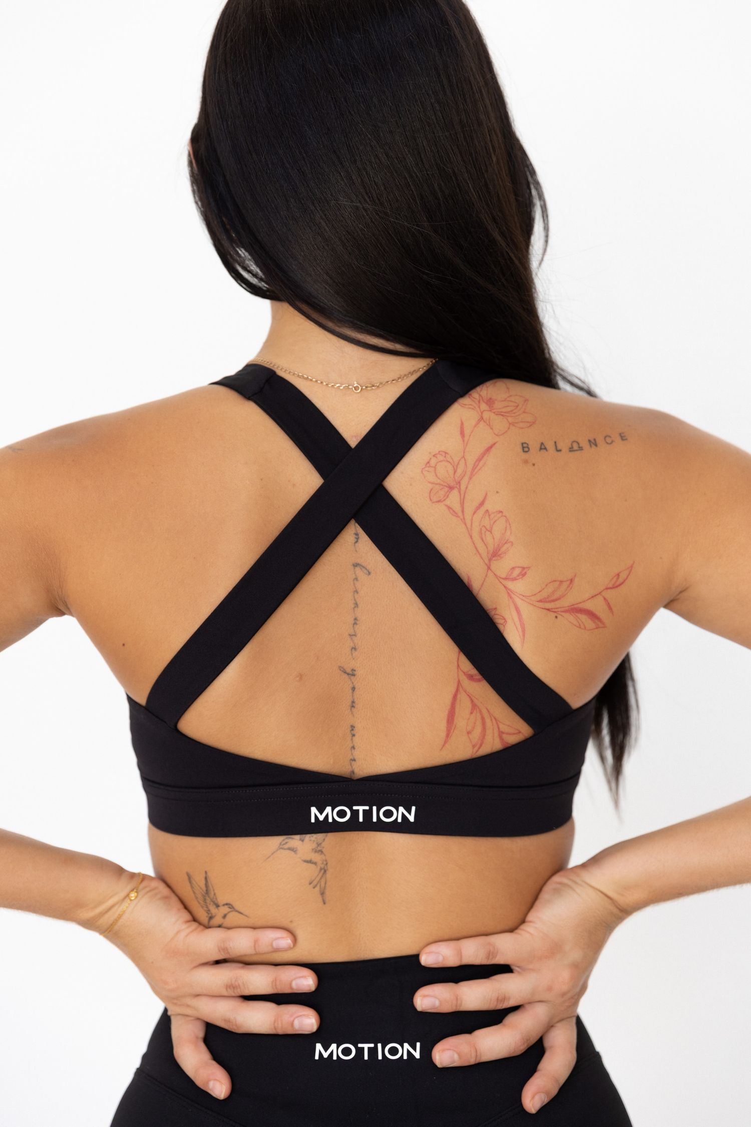 Black sports bra with cross-back design shown from multiple angles displaying back tattoos.