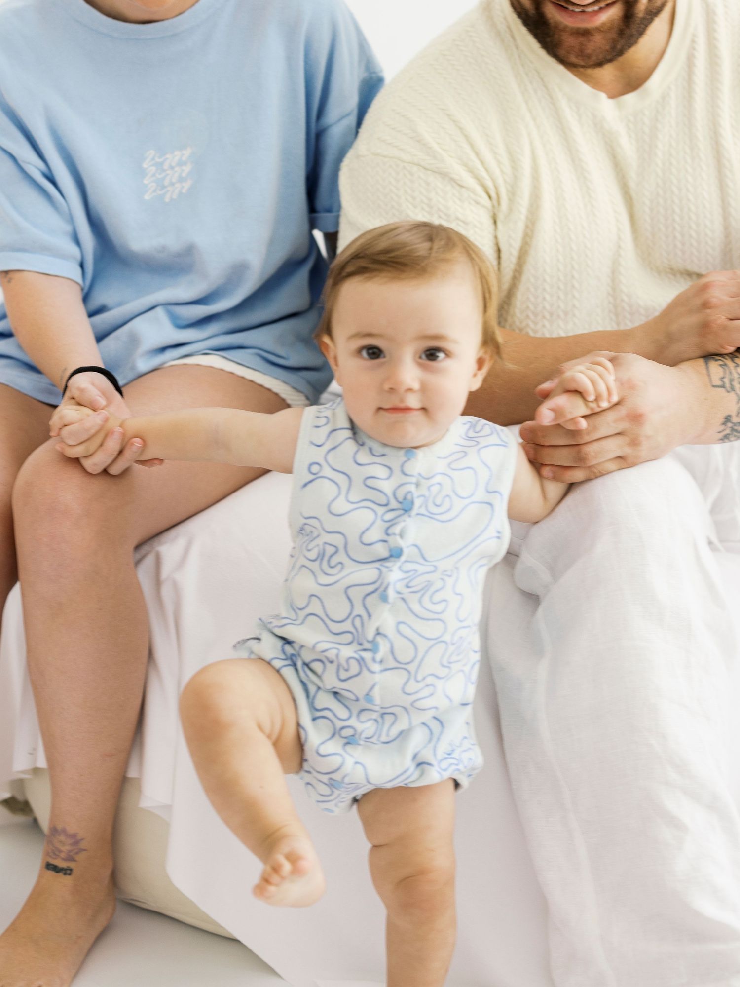 Family wearing coordinating blue and white sleepwear sits together on a white background showing matching outfits.