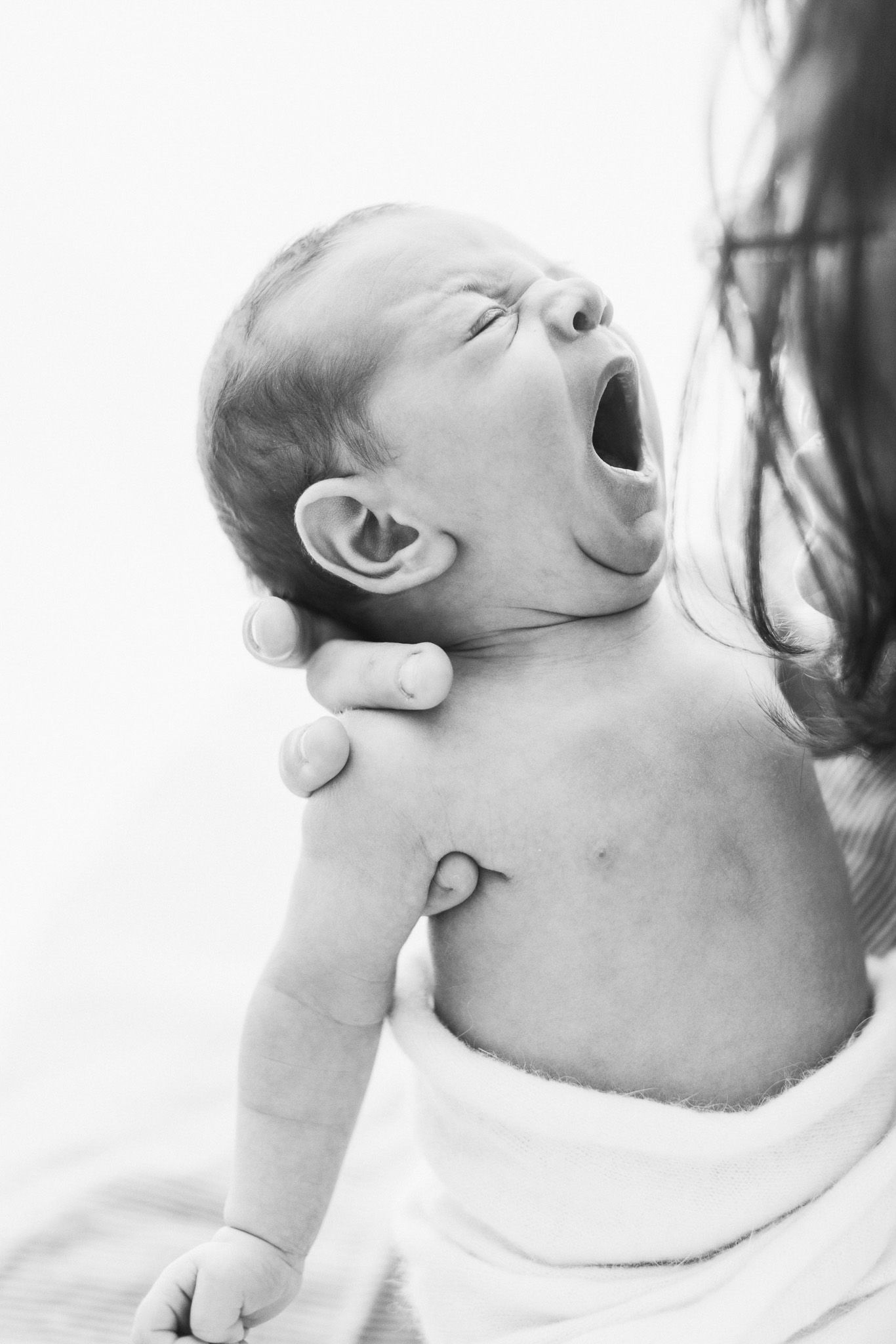 Black and white close-up profile shots of a baby laughing and expressing joy.