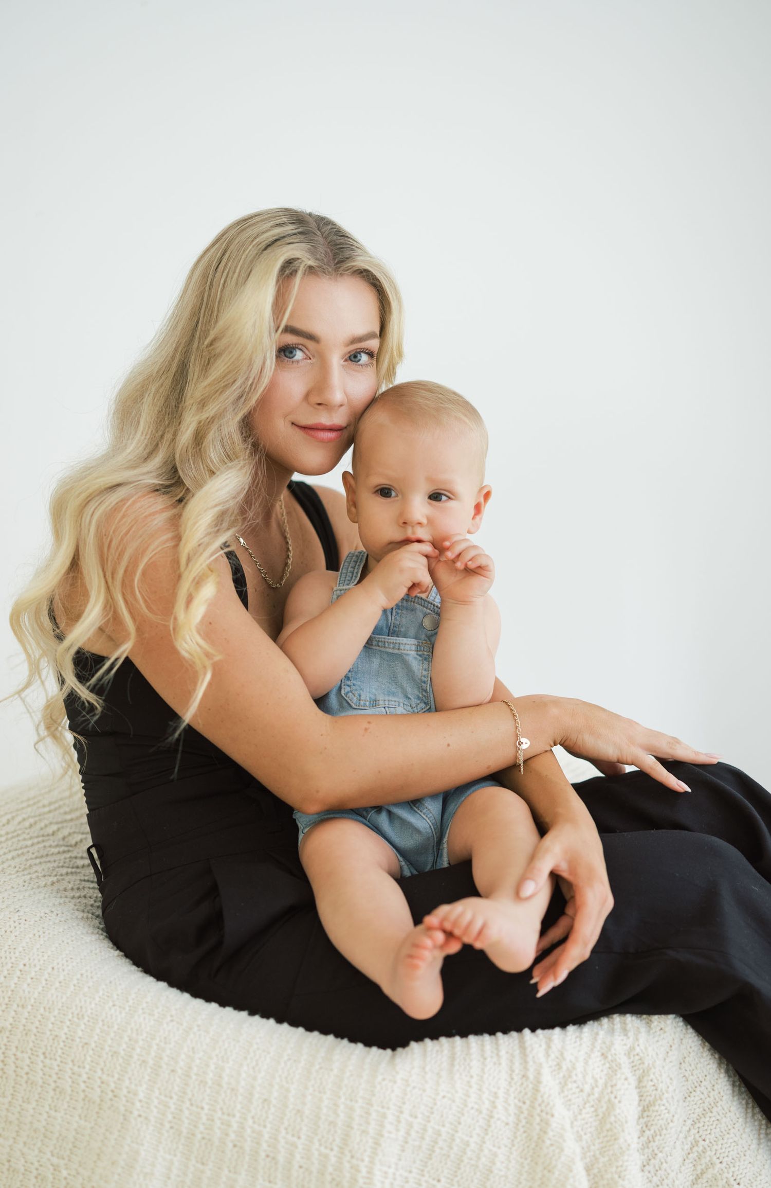 A series of intimate black and white portraits showing tender moments between a parent and baby on a light-colored couch.