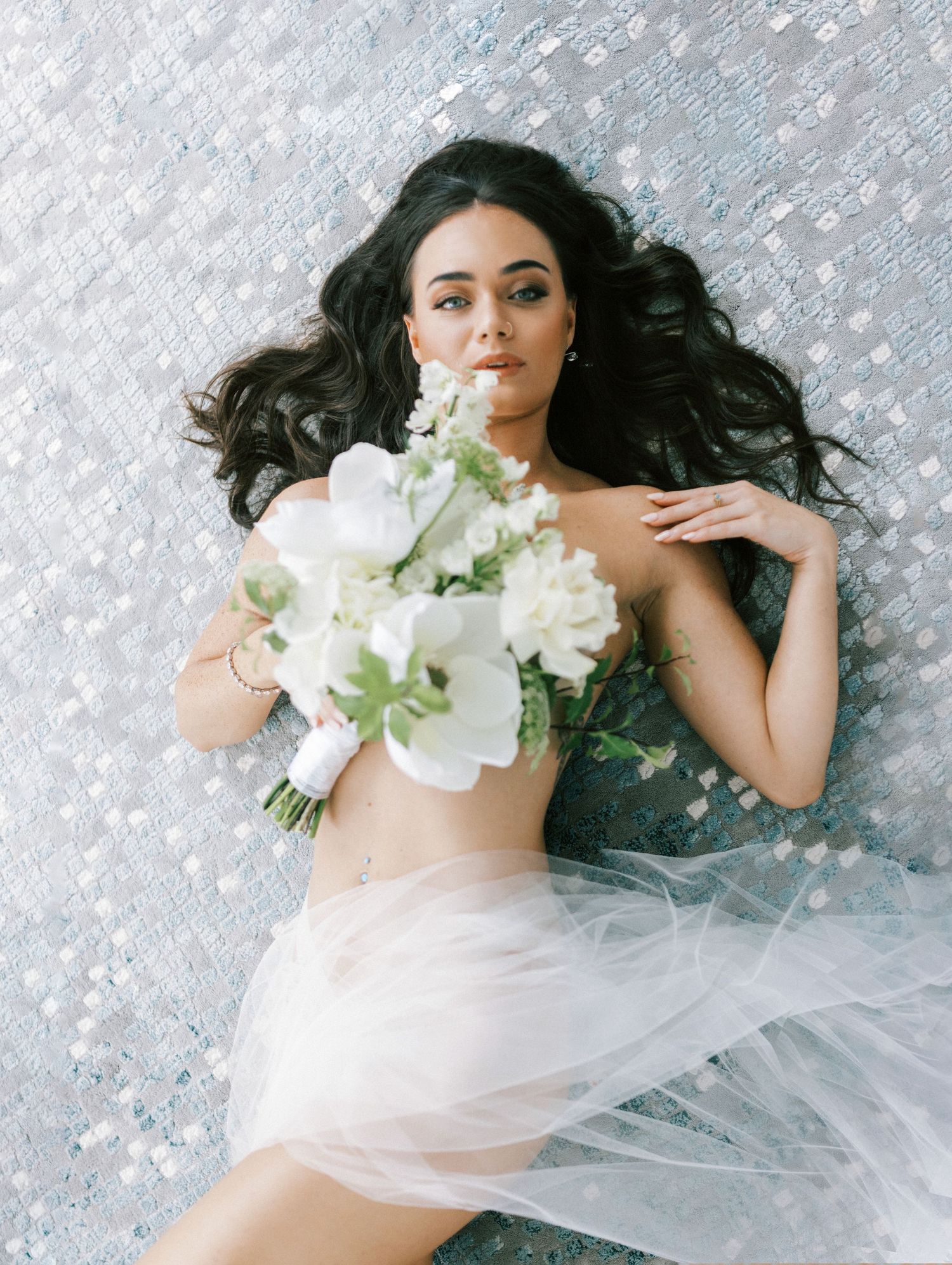 Artistic bridal boudoir photo series with white flowers and ethereal fabric.