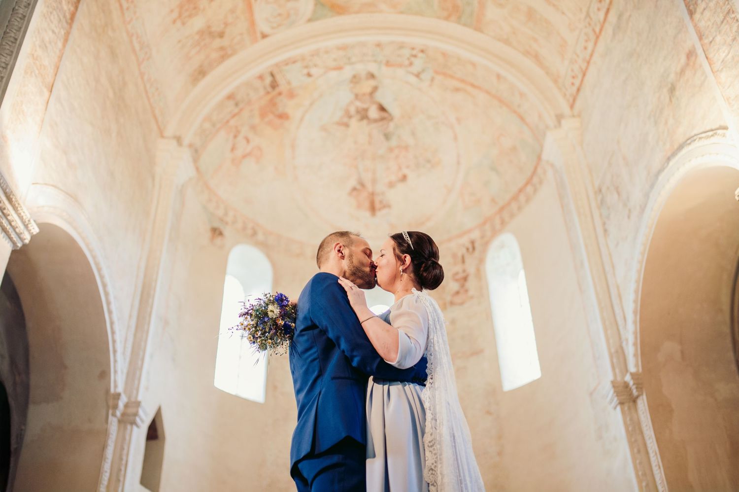 Two people share an intimate moment in a bright church interior with vaulted ceilings and ornate architectural details.Spiez Switzerland