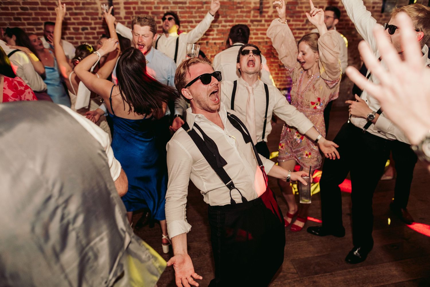 Wedding guests dance and celebrate together on a crowded dance floor during an energetic reception party.