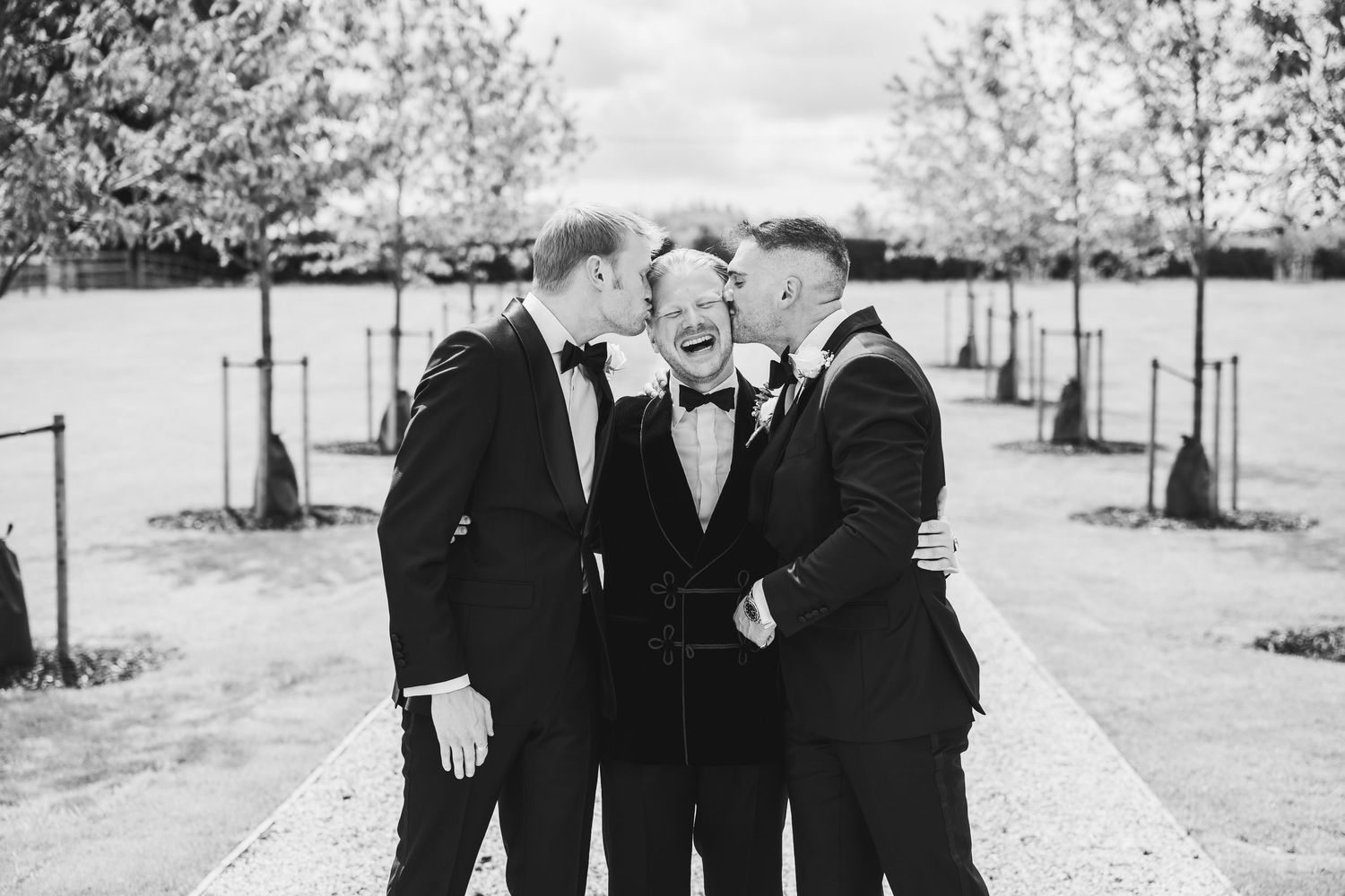 Black and white wedding party photos showing formal group poses on a sunny outdoor path.
