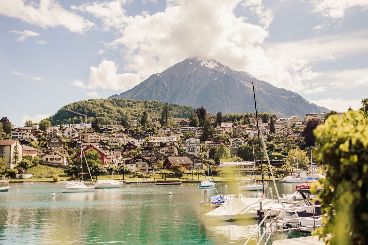 A scenic mountain village with boats moored in a tranquil lake harbor against the backdrop of Swiss Alps.Spiez switzerland destination