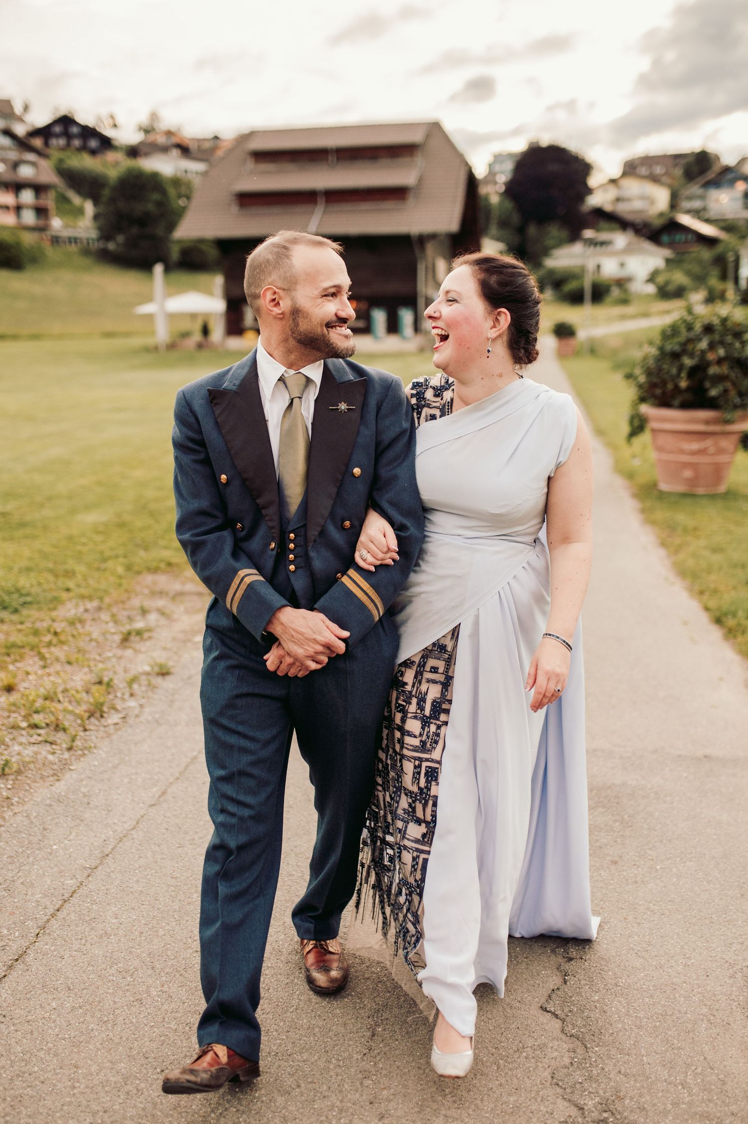 A couple shares a joyful laugh while walking together on a path, with the bride wearing a light blue dress.Spiez switzerland destination