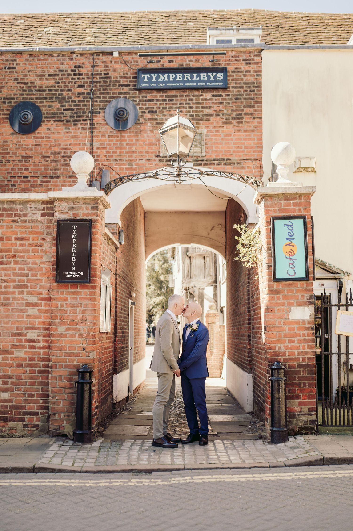 Couple posing in front of historic brick archway entrance with classic architecture.