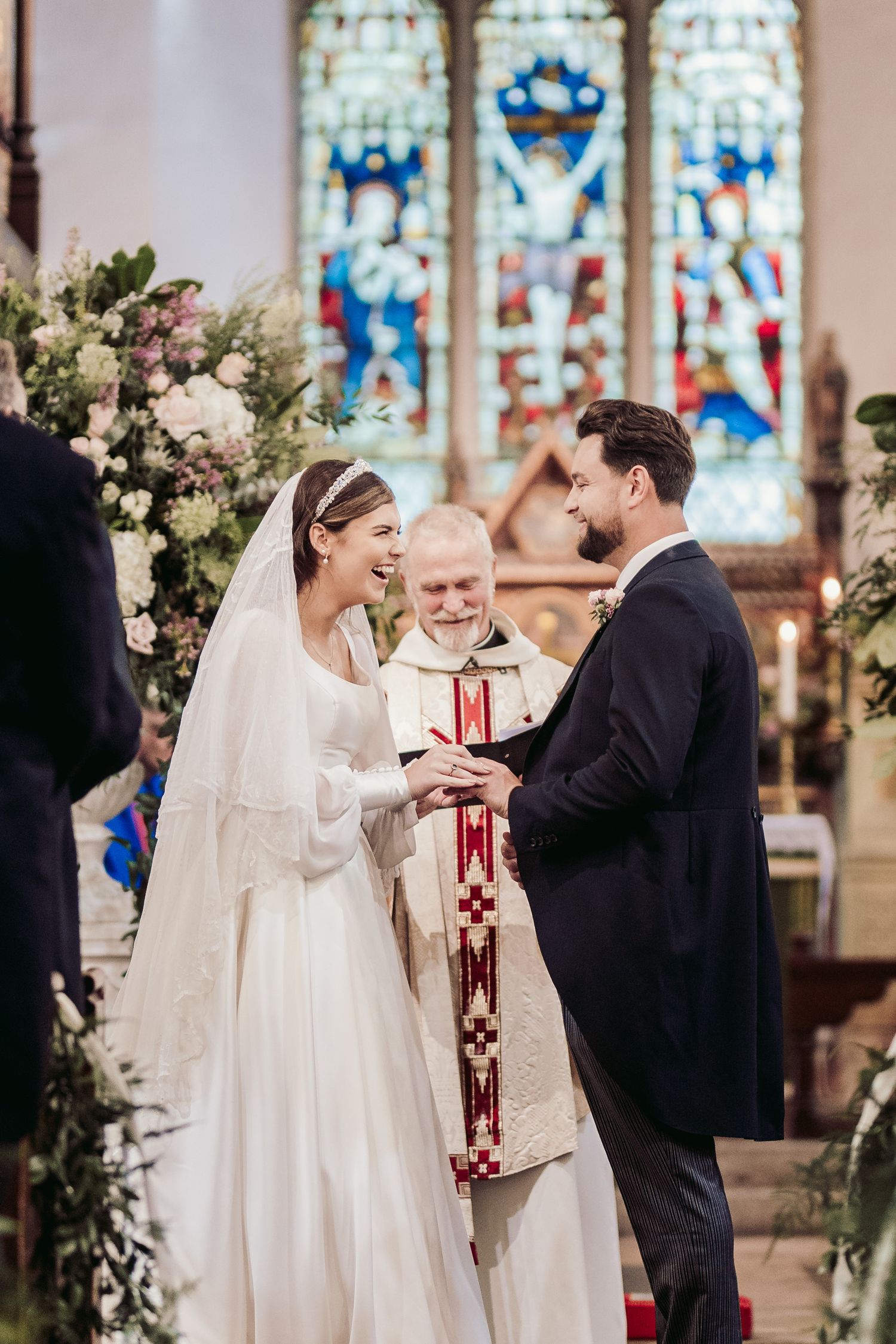 Traditional church wedding ceremony with stained glass windows and floral decorations.