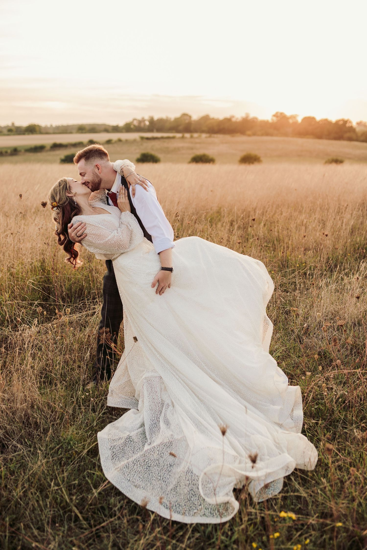 Romantic sunset photoshoot of newlyweds in a golden meadow.