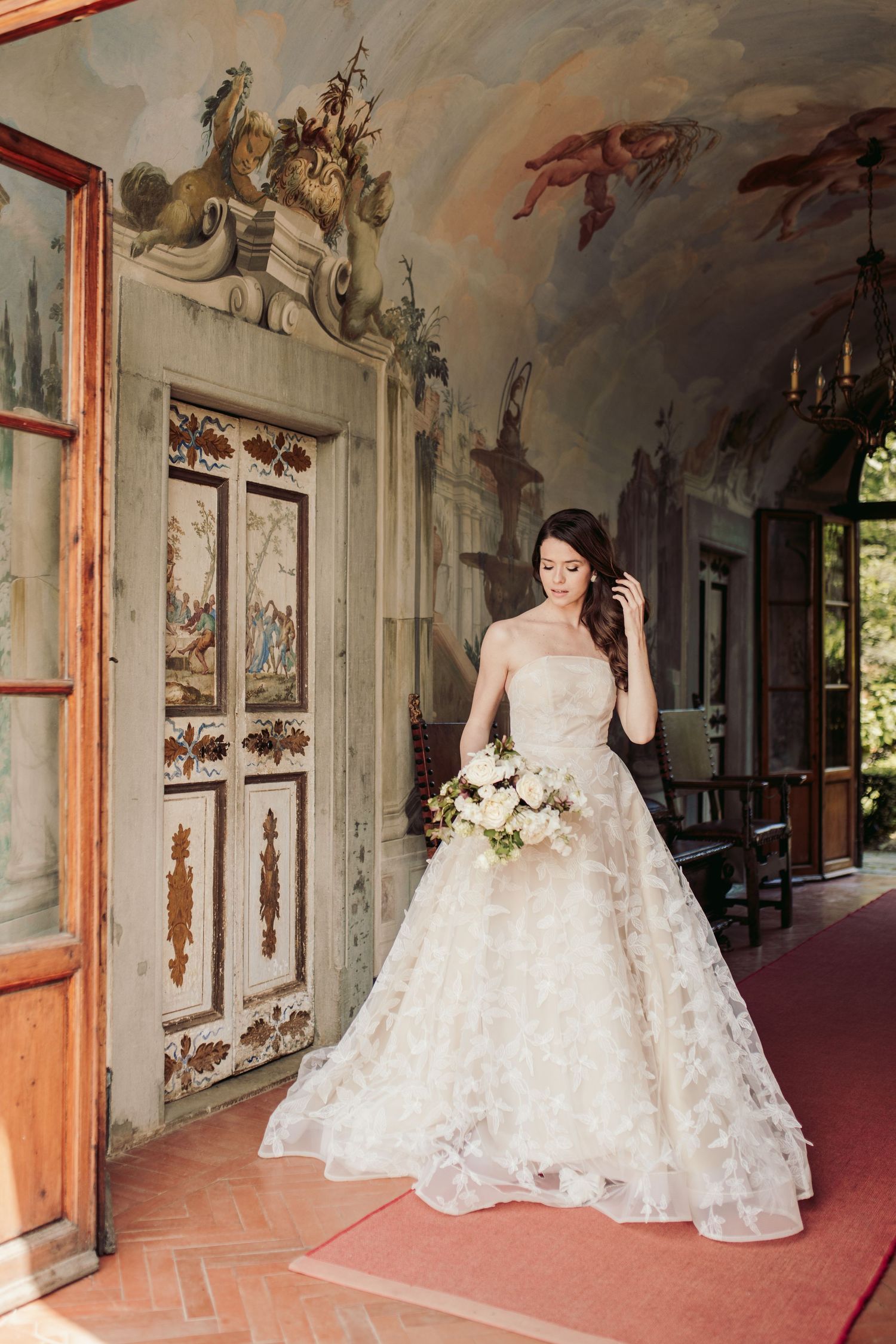 Elegant white wedding gown photographed in ornate Italian villa hallway.