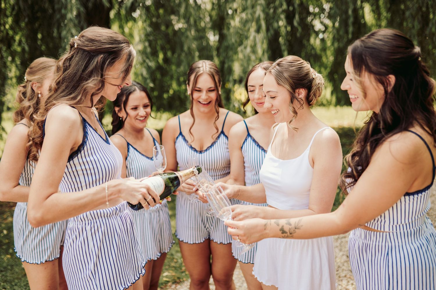 A group of women in blue and white striped dresses laughing and celebrating together at an outdoor event.