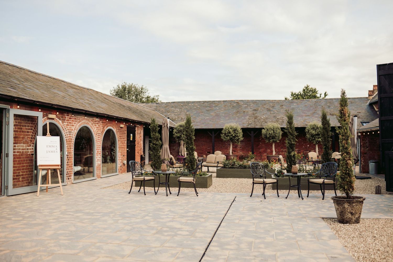 A panoramic view of an outdoor patio area with chairs and tables arranged along a brick building exterior.