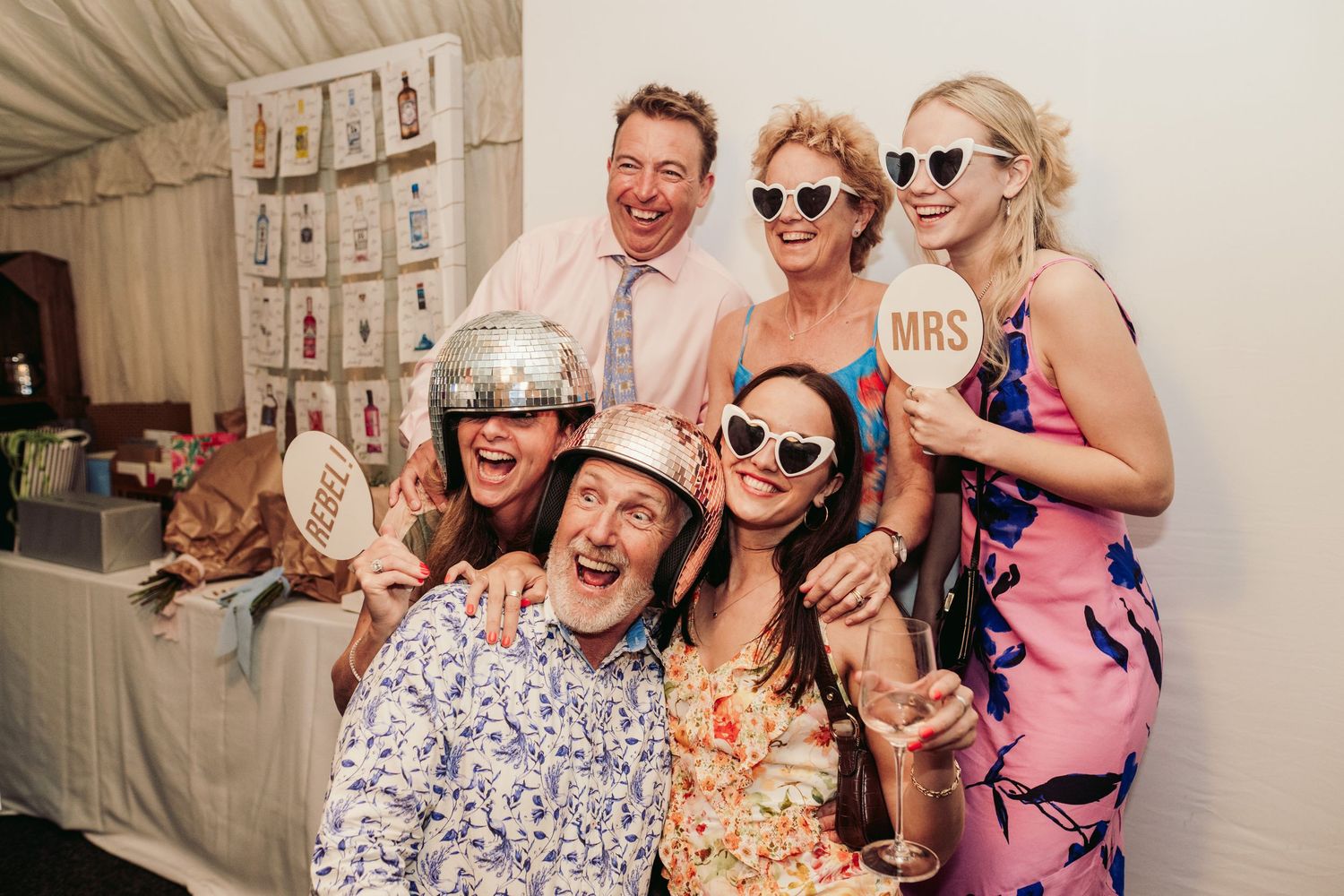 Wedding guests posing with props and sunglasses at a photo booth during reception celebrations.