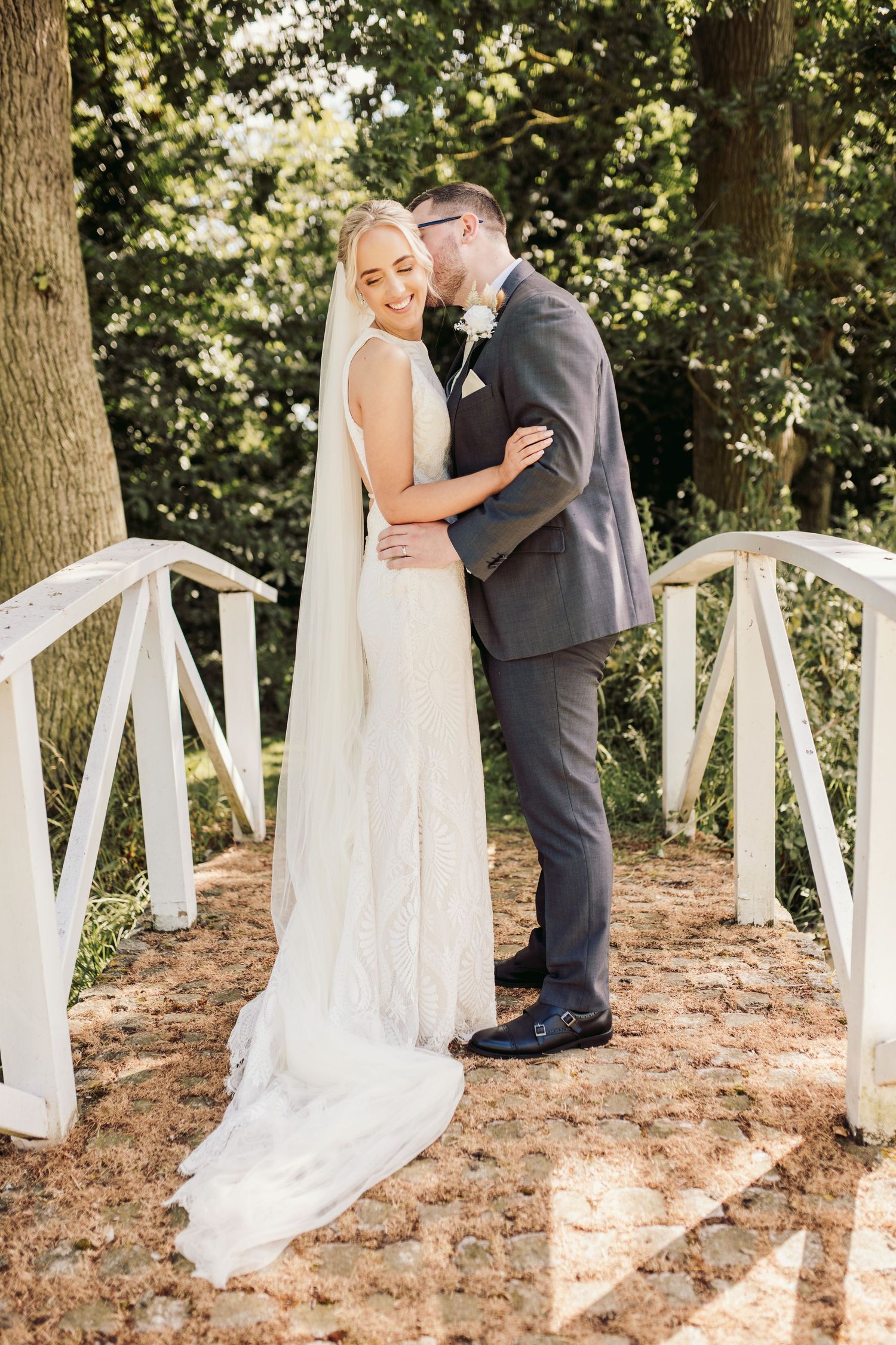 A romantic wedding photo series in a wooded area with white decorative elements.