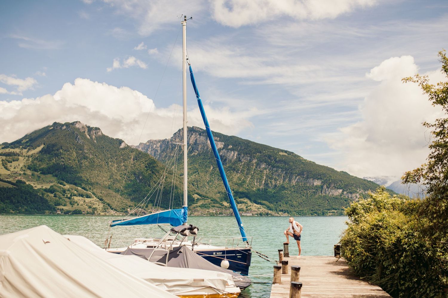 Sailboat docked at a pier on a mountain lake with blue sky and puffy white clouds overhead.Spiez switzerland destination wedding