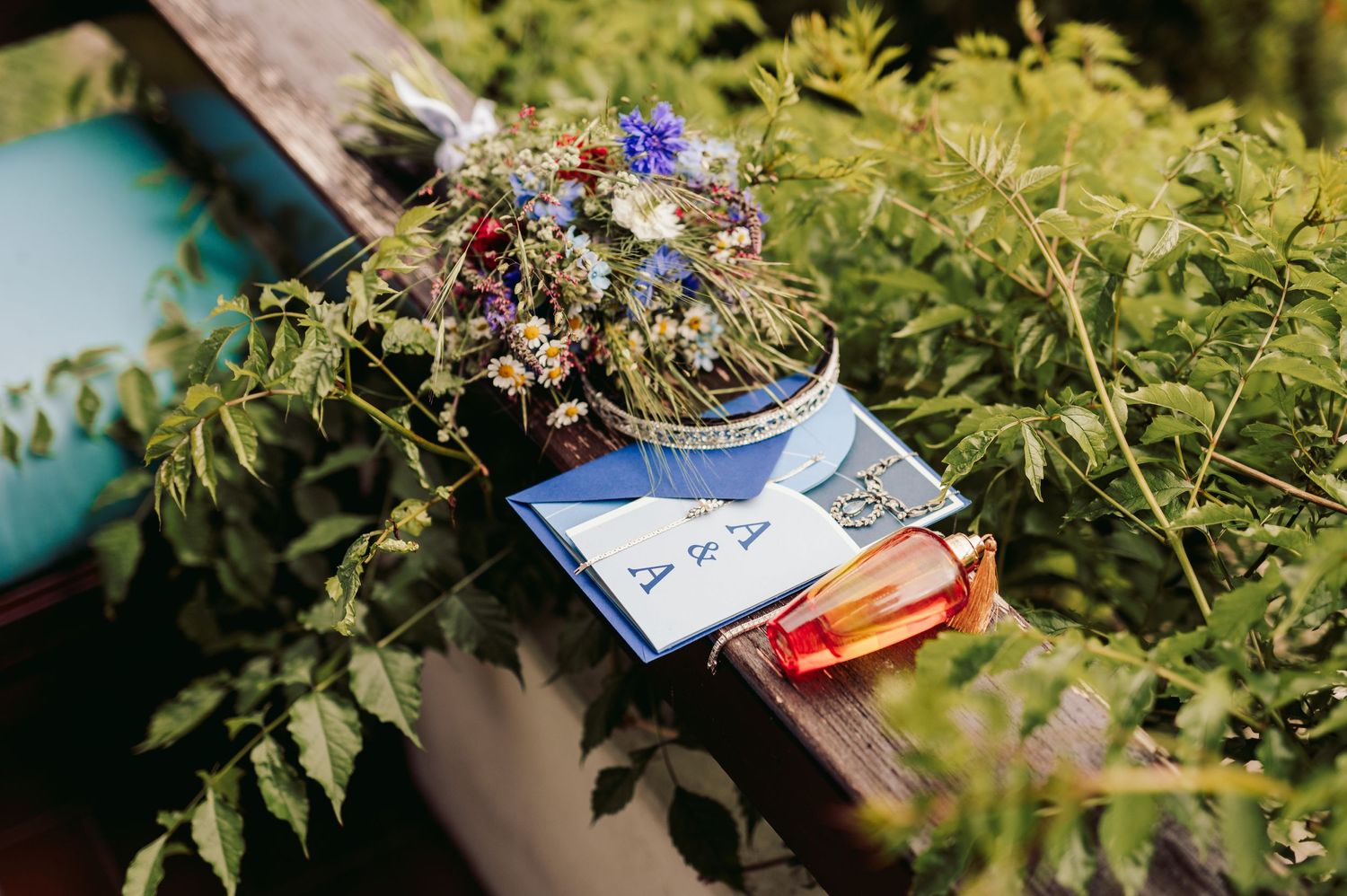 Small bouquet of dried flowers on a wooden bench surrounded by green foliage and a blue book beneath.Spiez switzerland destination wedding
