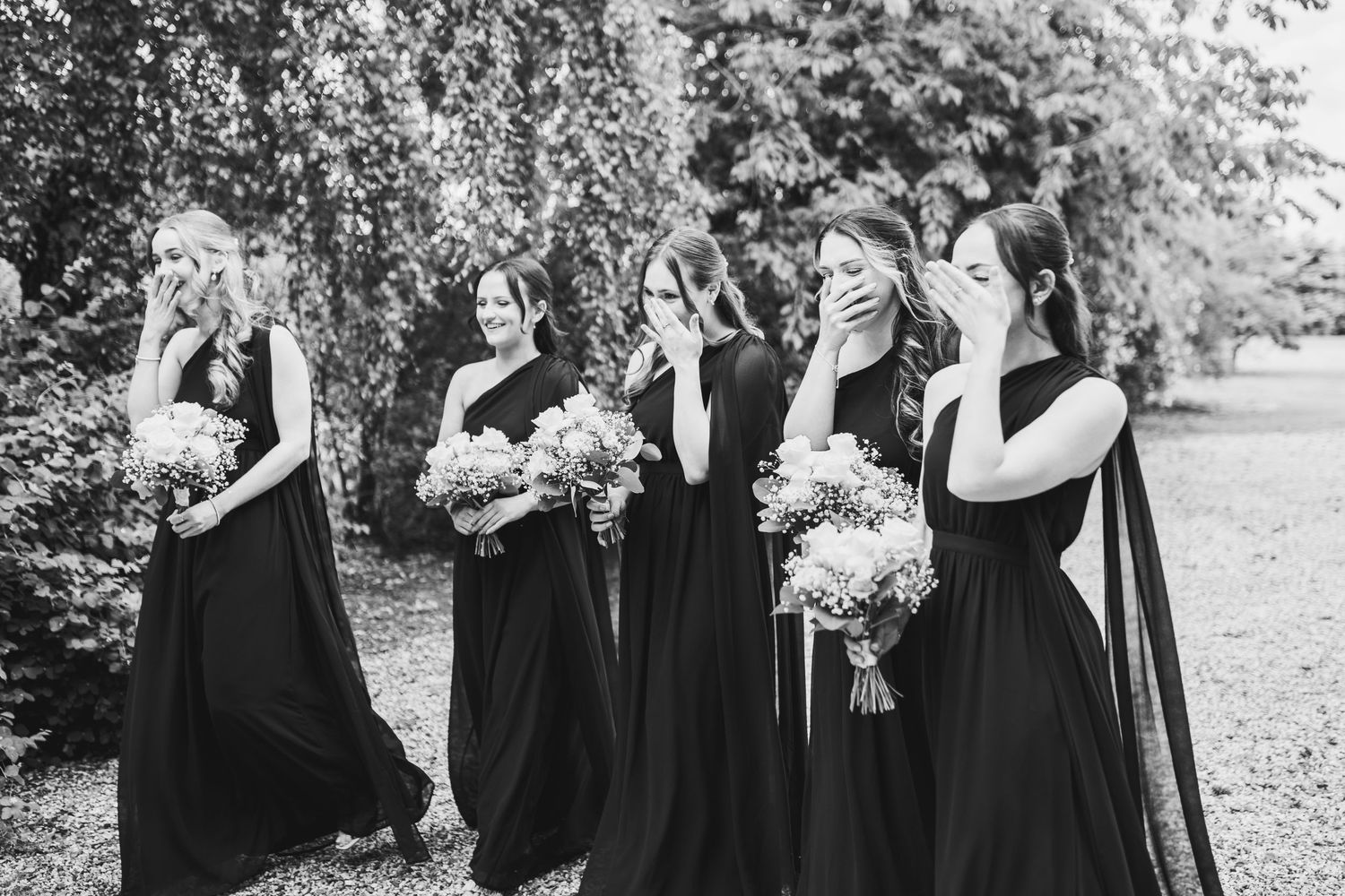 A series of black and white photos showing a bridal party in formal attire posing outdoors in a garden setting.