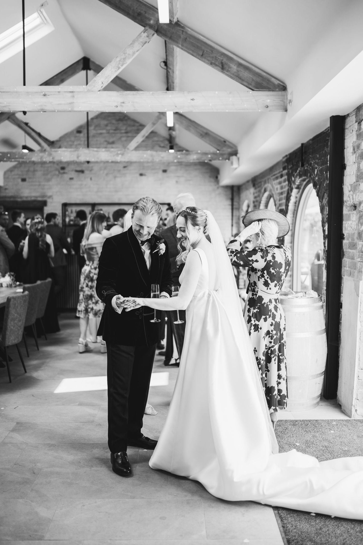 Black and white photo series of couples dancing at a rustic barn wedding reception with exposed beams and white decor.