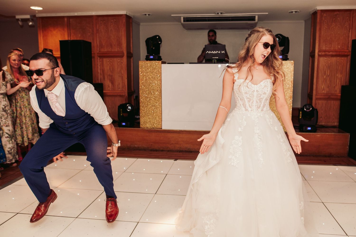 Looking energetic, a dancing couple on their wedding day showing fun moves on the reception dance floor.