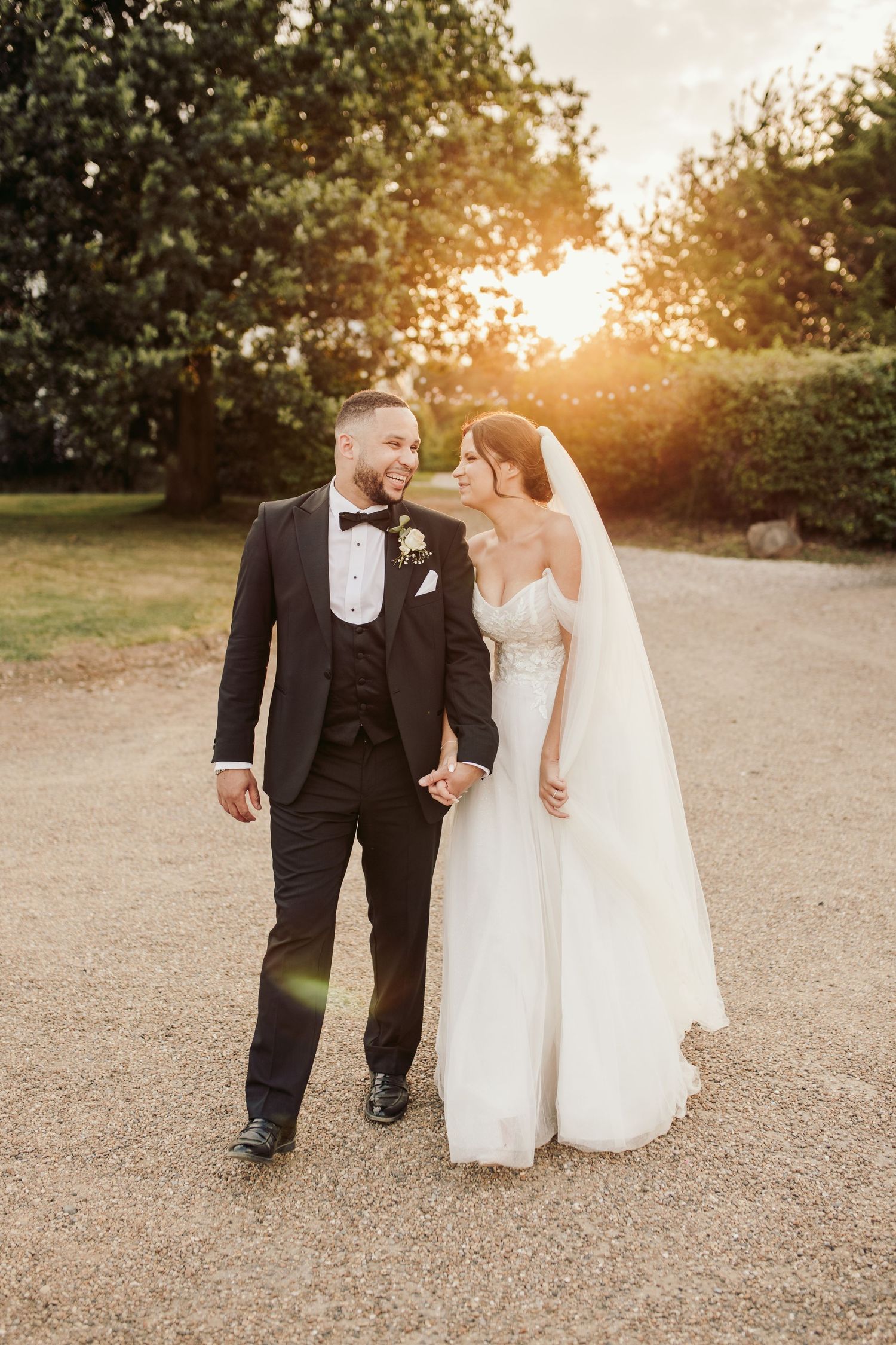 Couple takes romantic sunset photos on a gravel path during their wedding day.