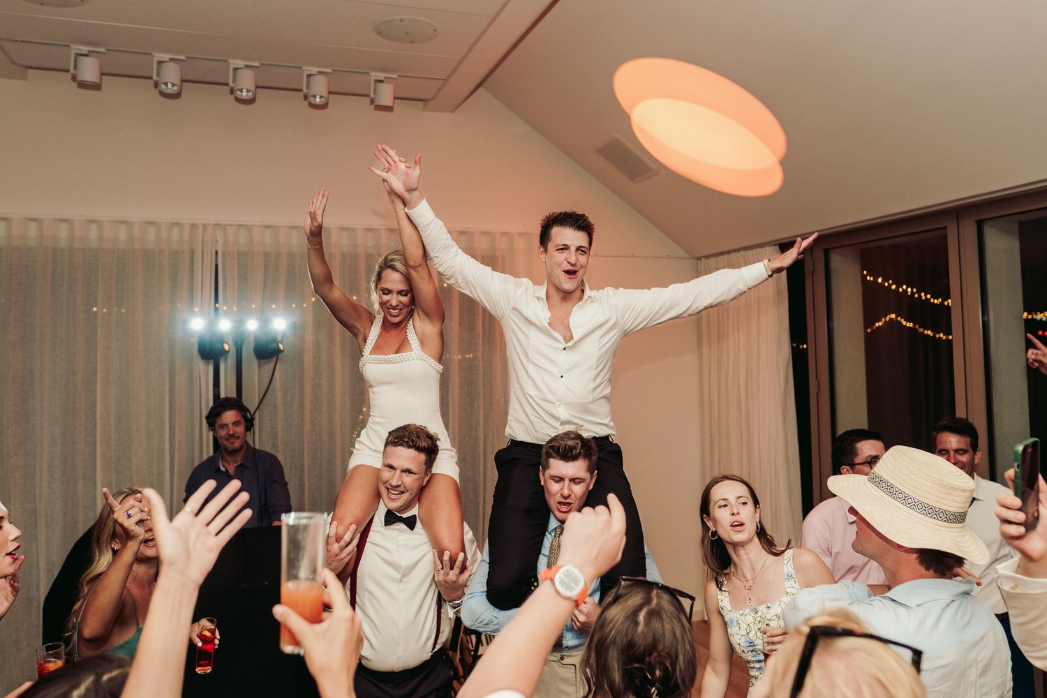 Energetic wedding party celebration with guests jumping and dancing on the dance floor.