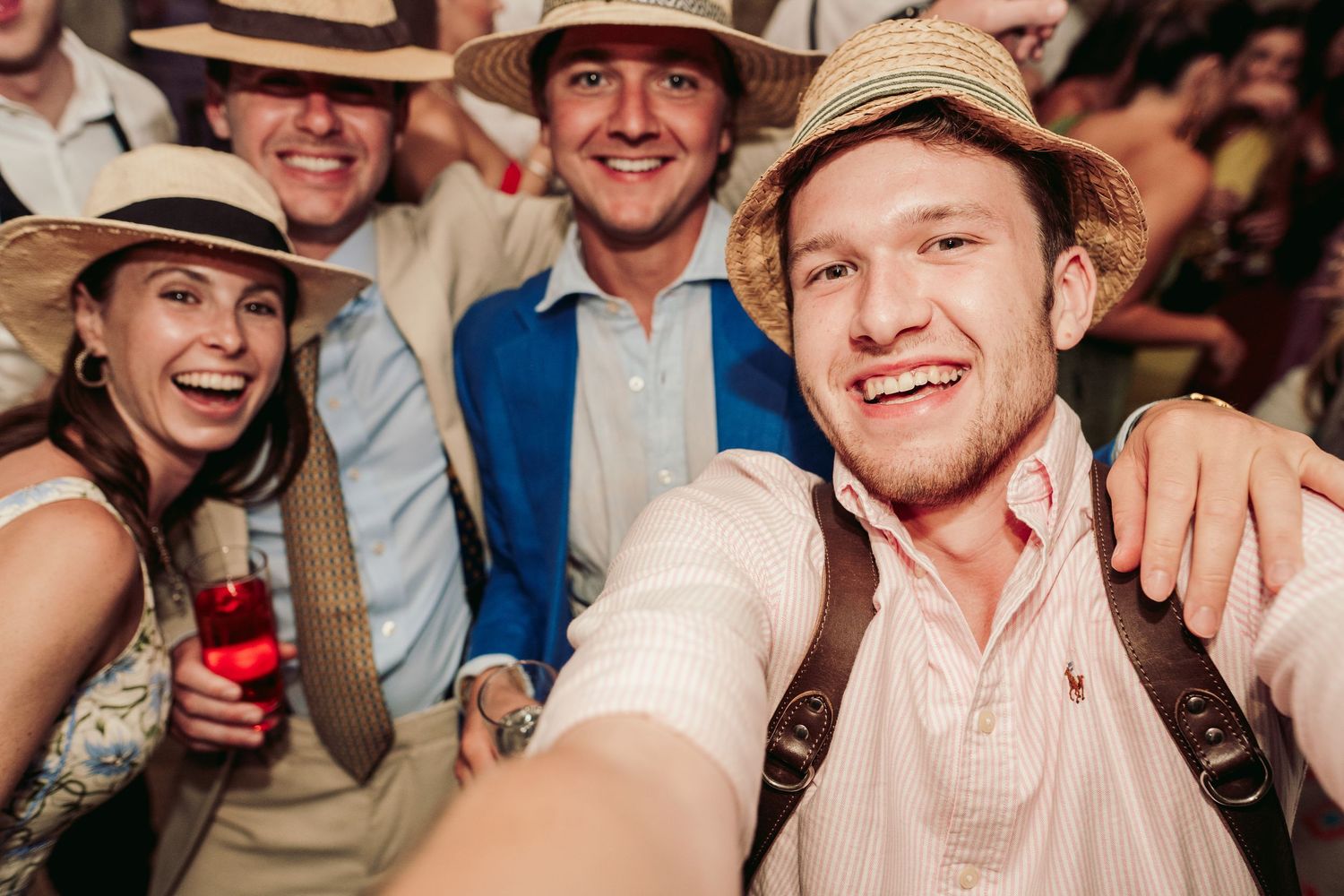 Wedding guests wearing straw hats and celebrating at a rustic reception venue.
