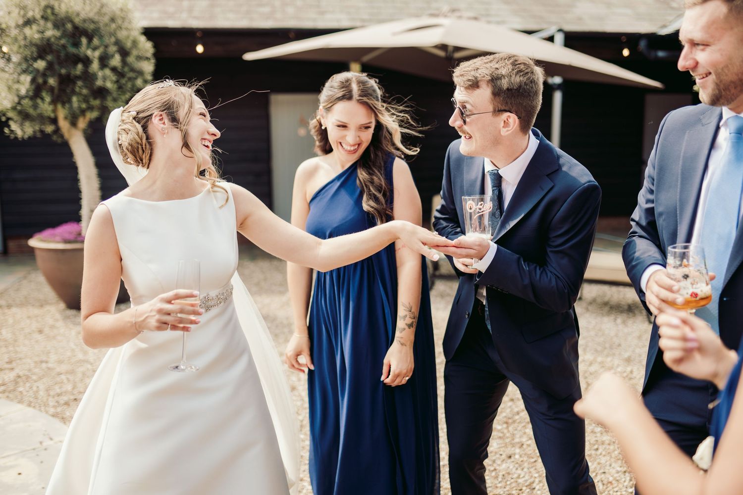 Wedding party celebrates joyfully during outdoor reception in formal attire.