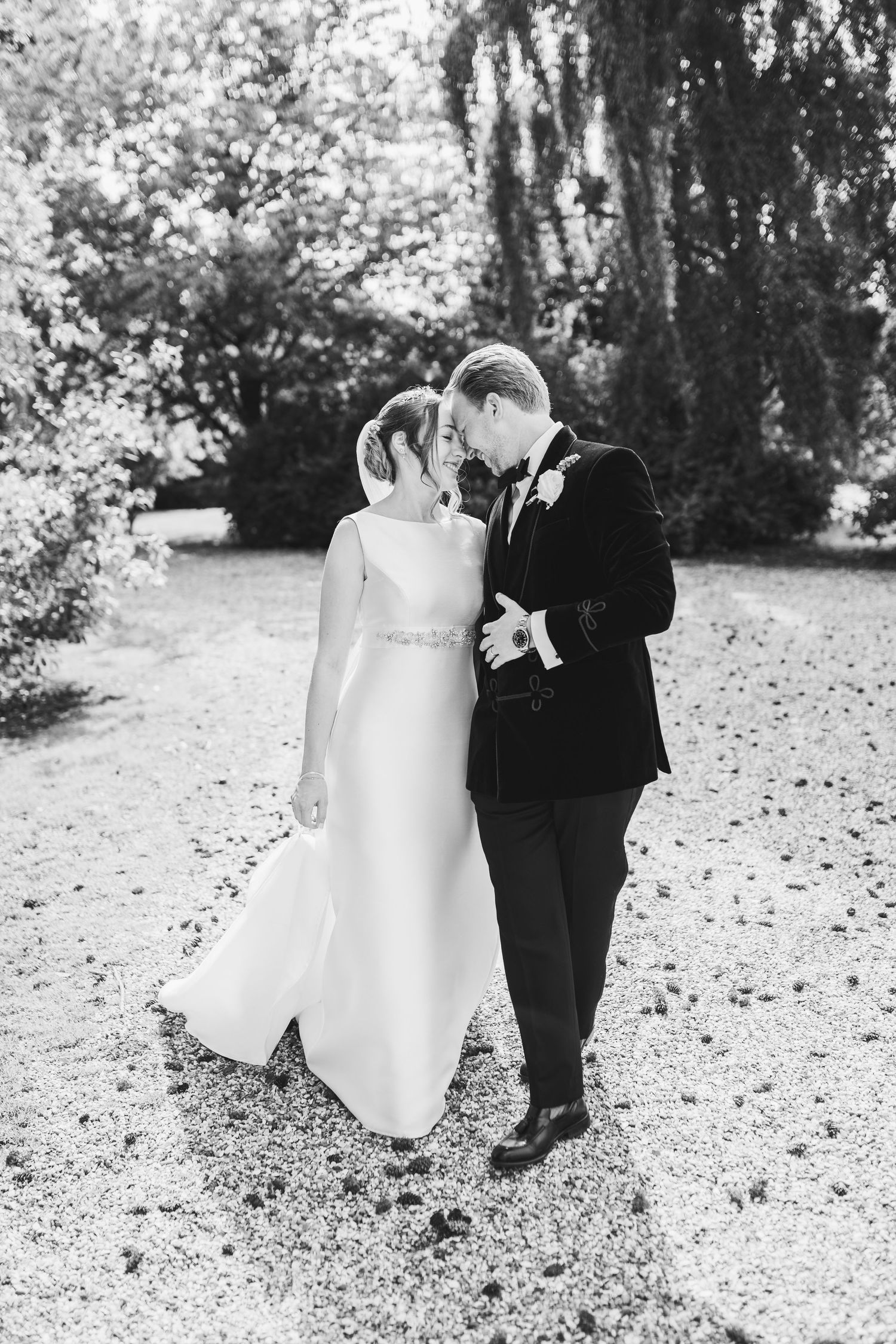 A black and white photo series of a bride and groom walking together through scattered autumn leaves.