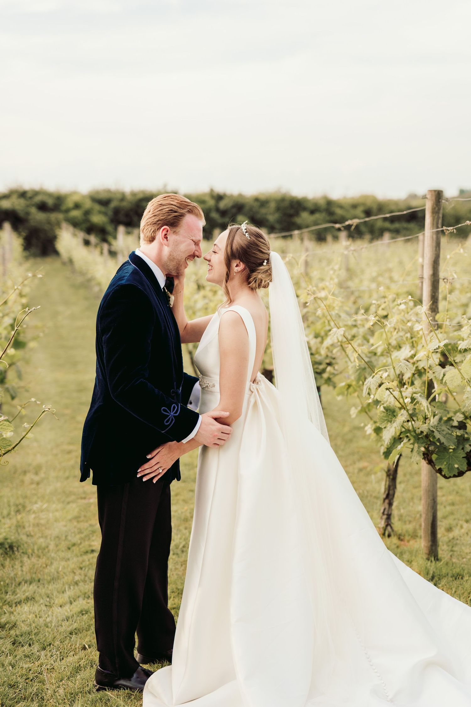 A romantic wedding moment captured in a vineyard with the bride wearing a flowing white gown and veil.