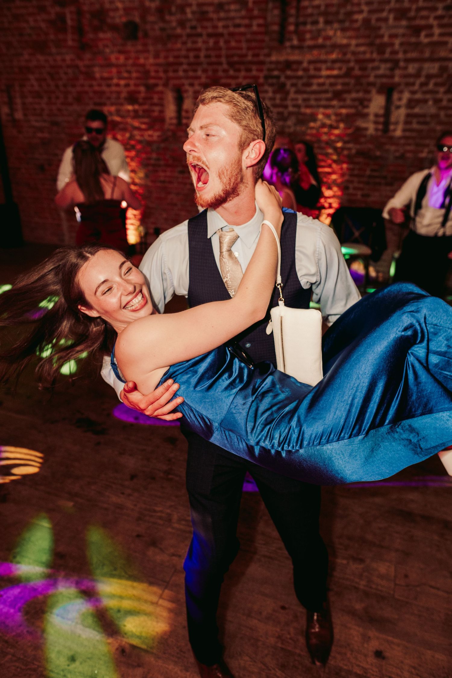 A sequence of dance moves shows a couple performing a dramatic dip on a brick-walled dance floor with colorful lighting.