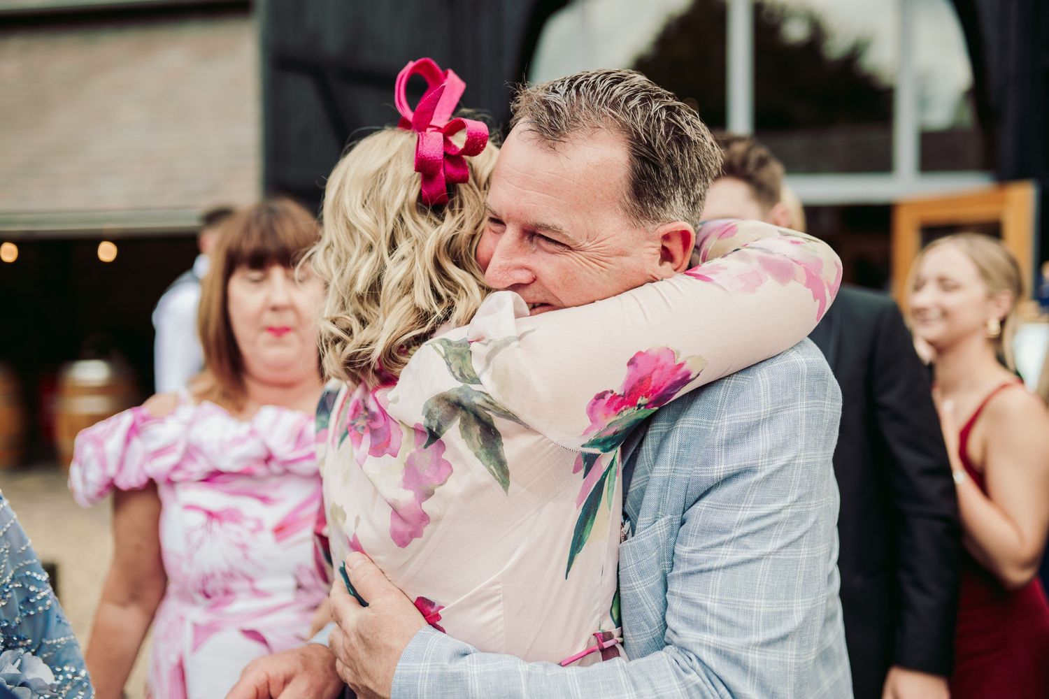 A couple shares a romantic kiss during their wedding dance while pink flower petals fall around them.