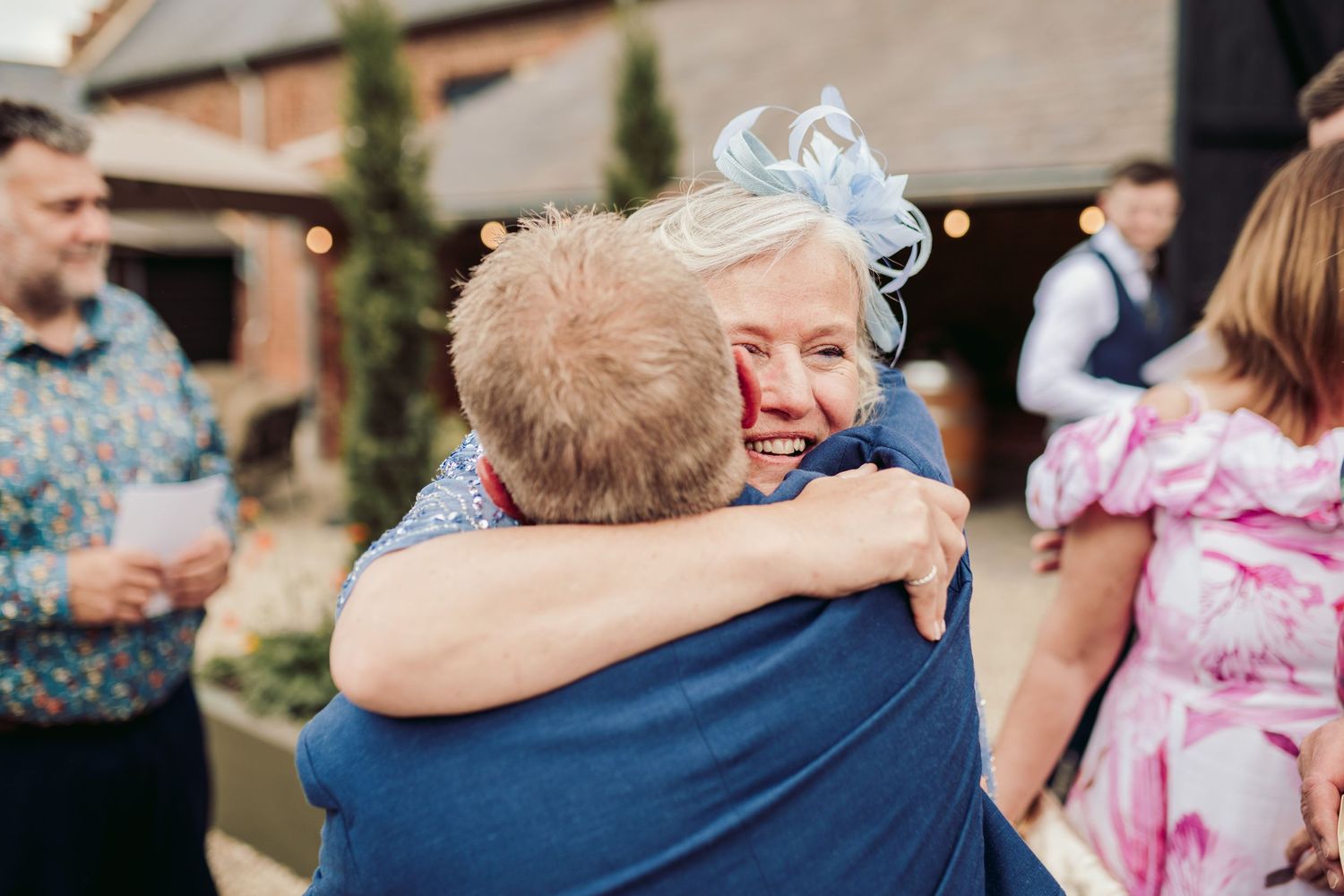Wedding guests embrace and celebrate during an emotional outdoor reception.