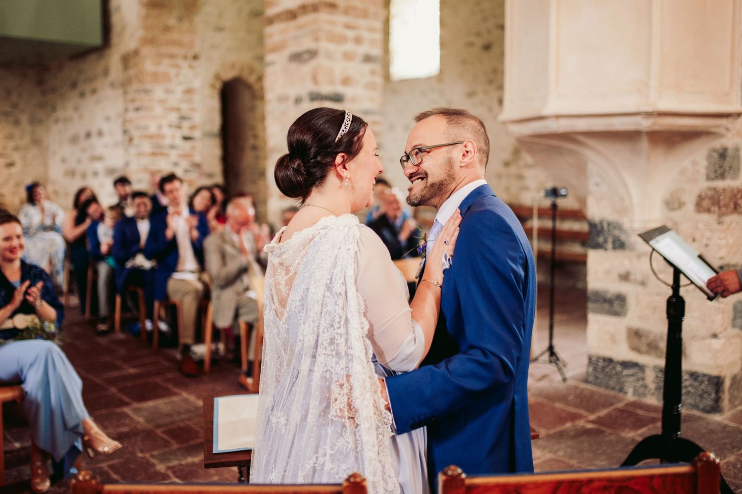 A couple shares a tender moment during their wedding ceremony inside a historic stone church with brick walls. Spiez switzerland destination