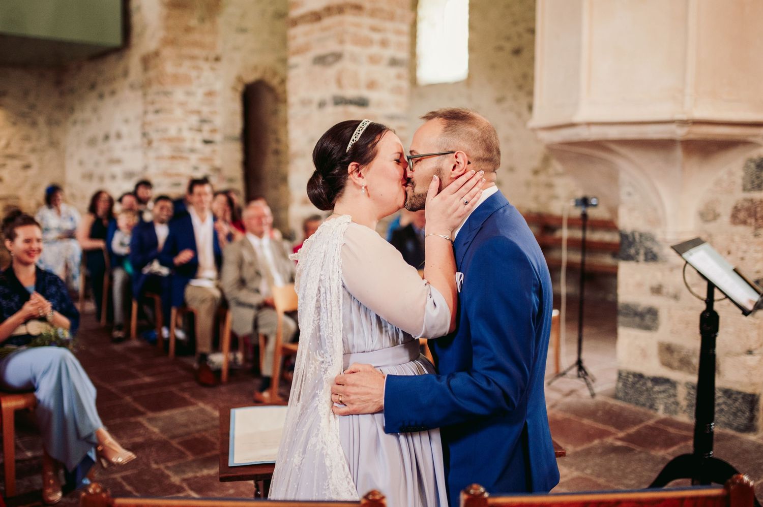 Newlyweds share their first kiss as husband and wife at a rustic brick church ceremony surrounded by guests. Spiez switzerland destination