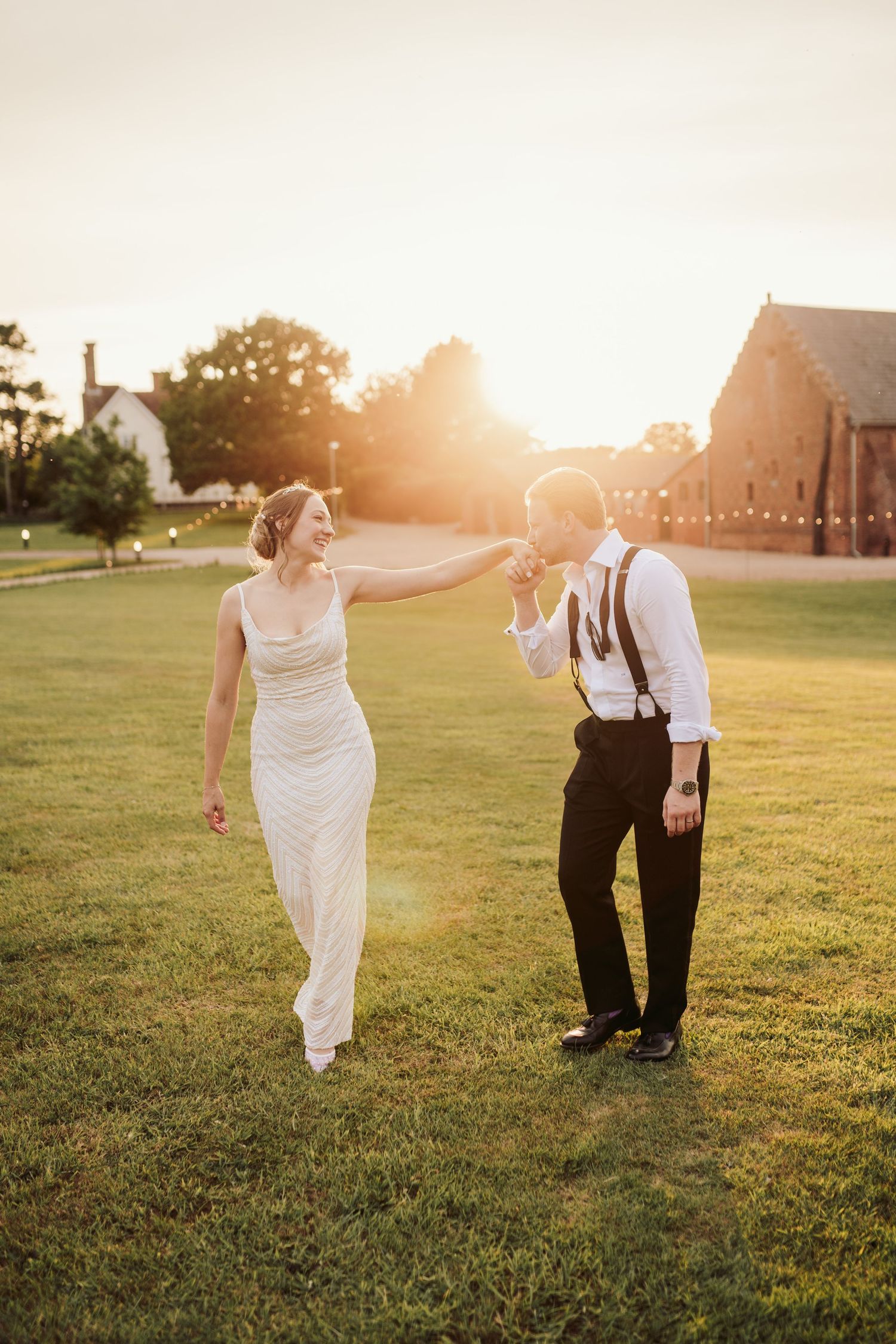 Couple dancing in a sunlit field during golden hour at their wedding celebration.