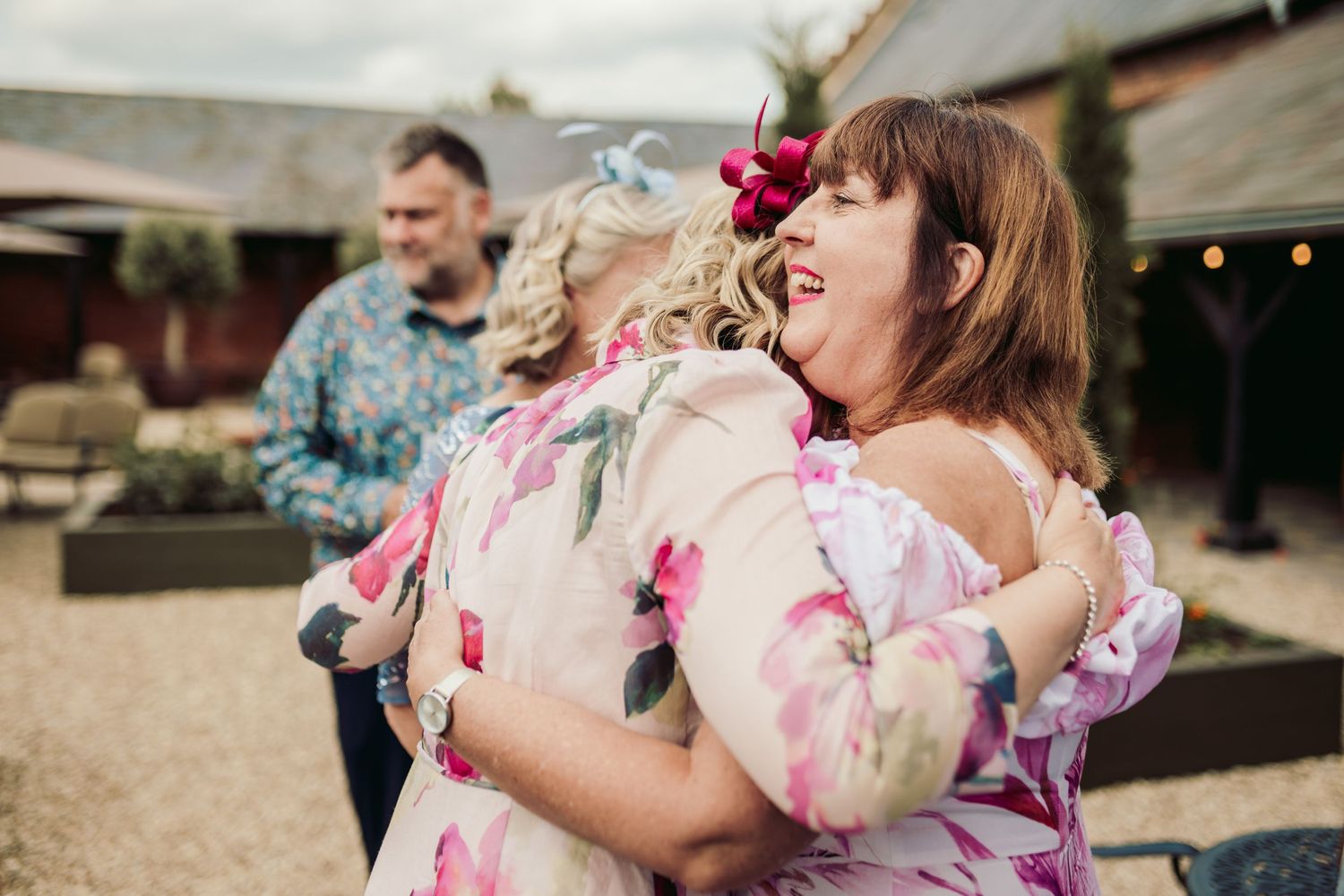 A group of women wearing floral yukatas embrace and laugh together at a traditional Japanese festival.