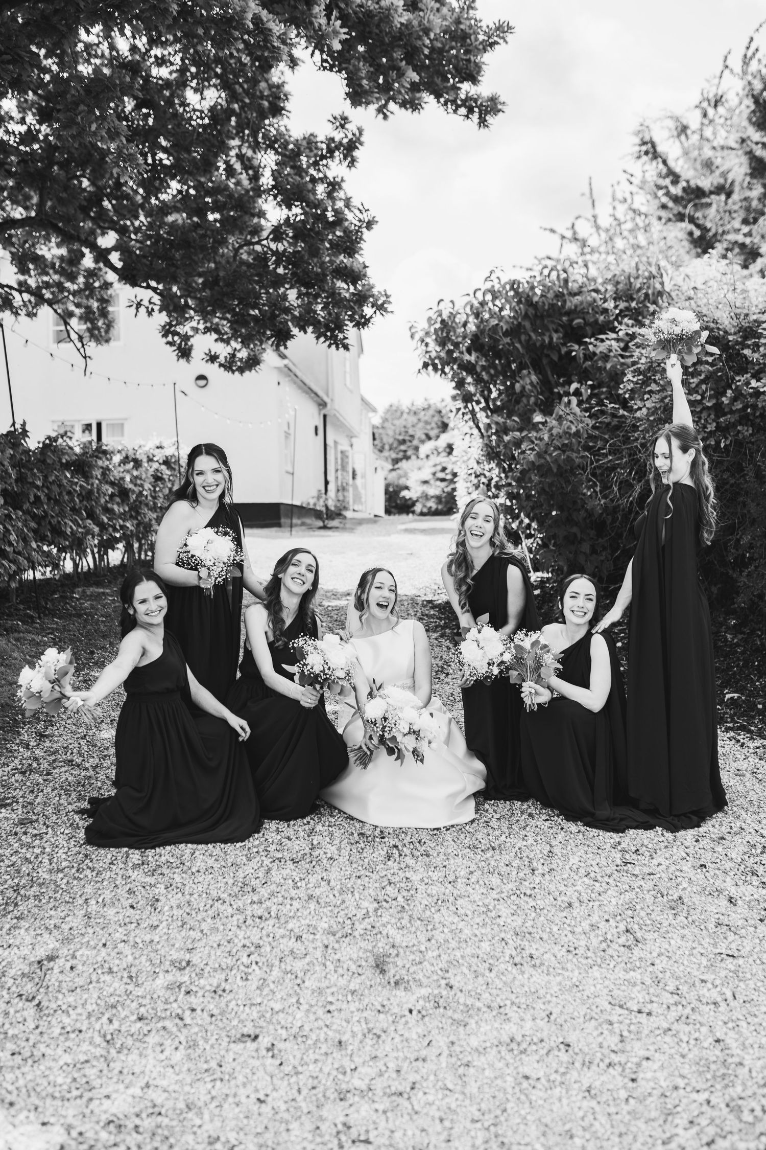 A black and white photo showing a group in formal attire sitting together on a grassy hill.