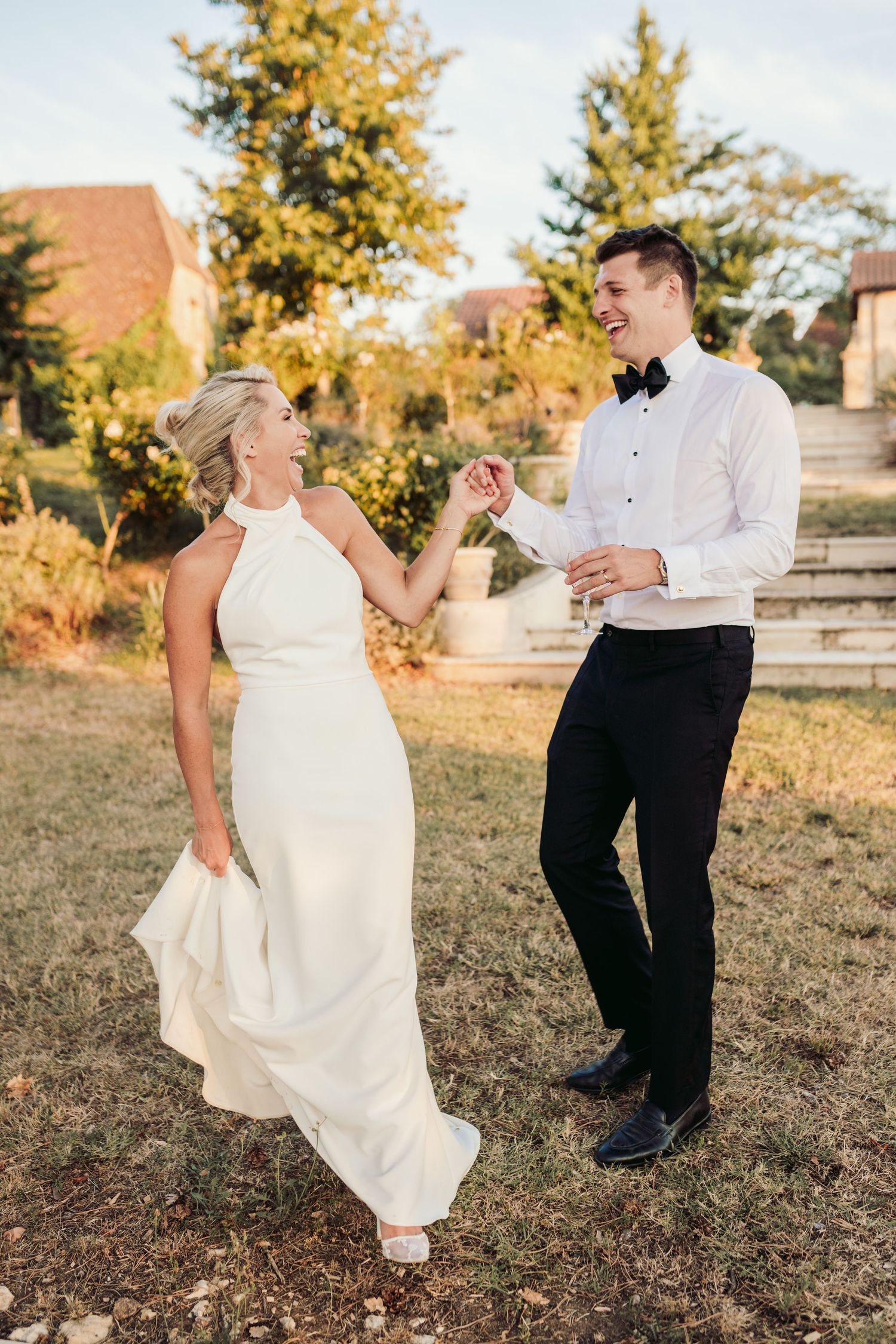 A couple shares playful moments in their wedding attire during a golden hour outdoor photoshoot.